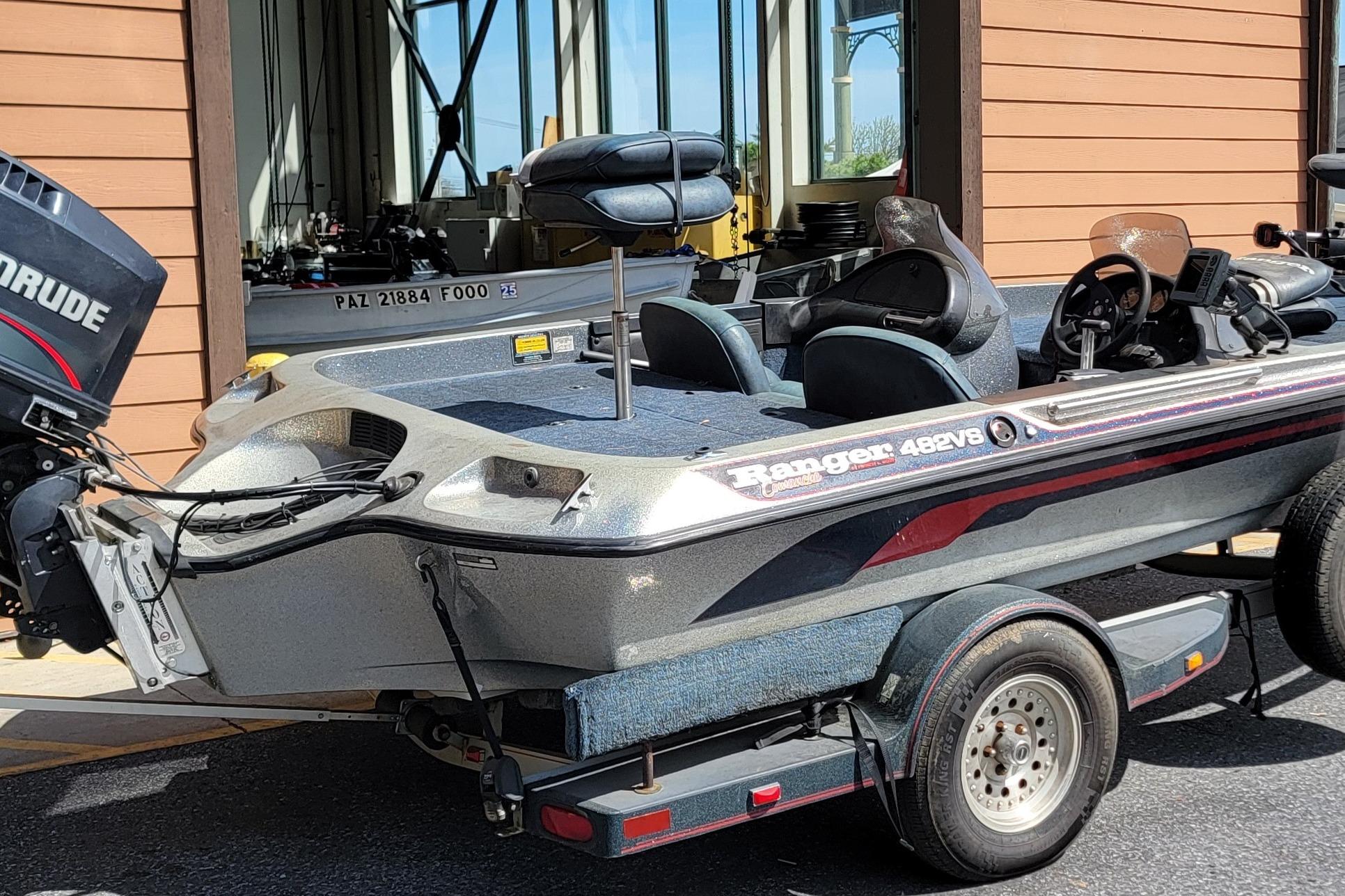 1995 Ranger boat with Evinrude motor, parked on a trailer near a building.