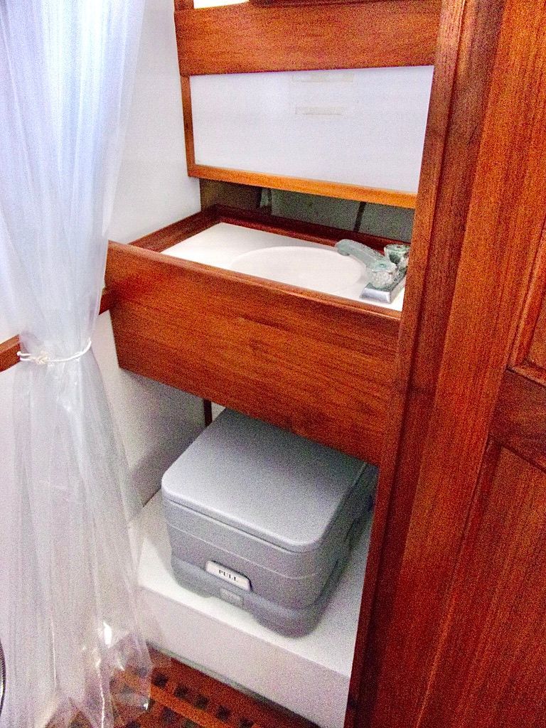 1976 CHB Trawler bathroom with wooden cabinetry and portable toilet.