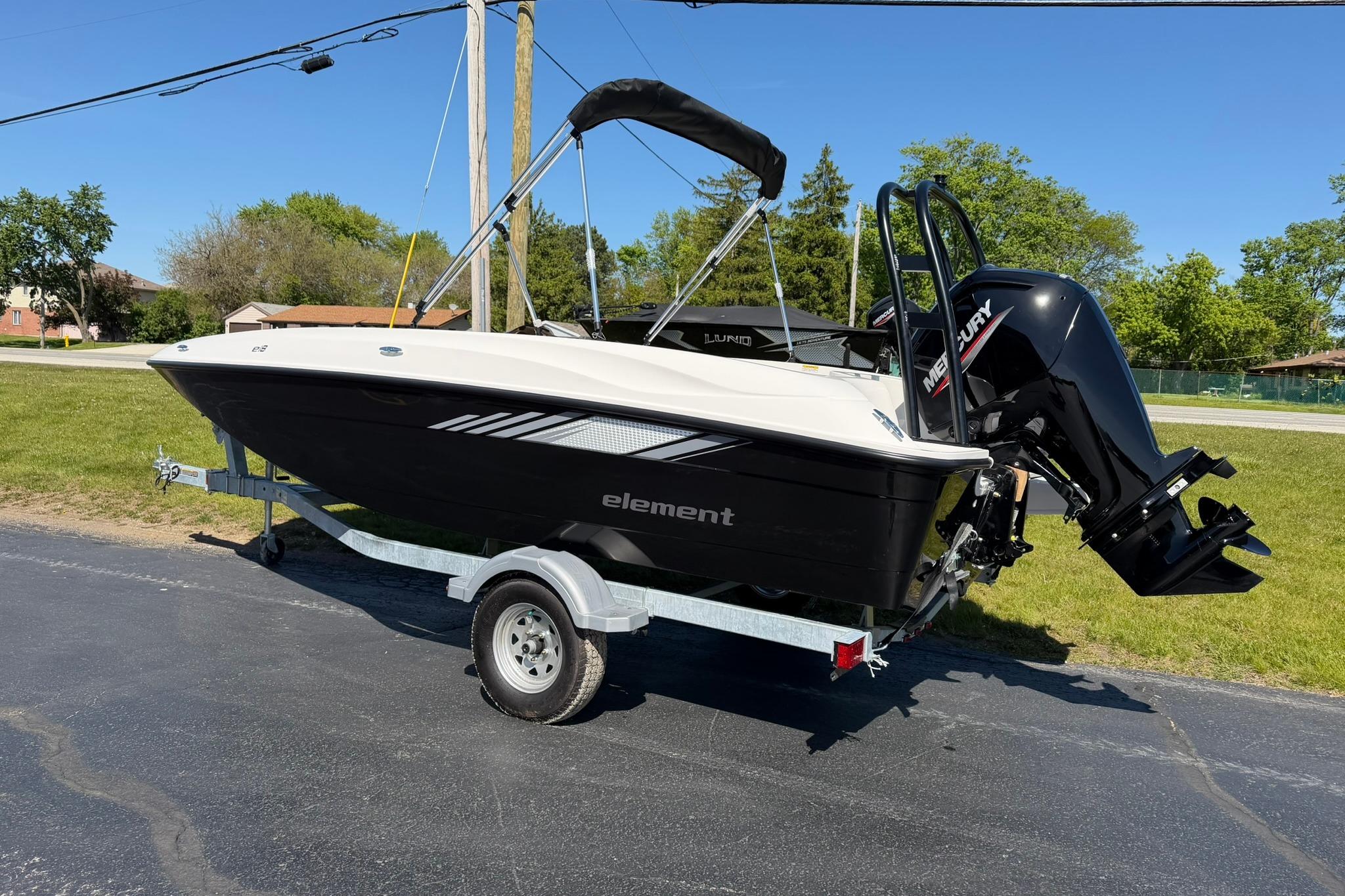 2026 Bayliner Element E18 boat on trailer, parked outdoors on sunny day.
