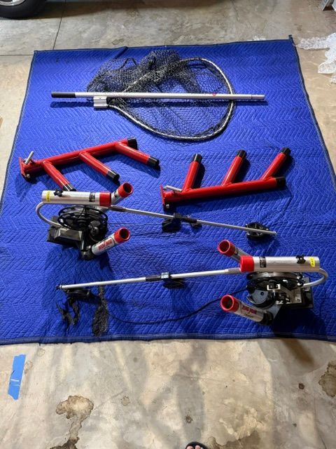 Various fishing rod holders and nets are laid out on a blue blanket on the floor.