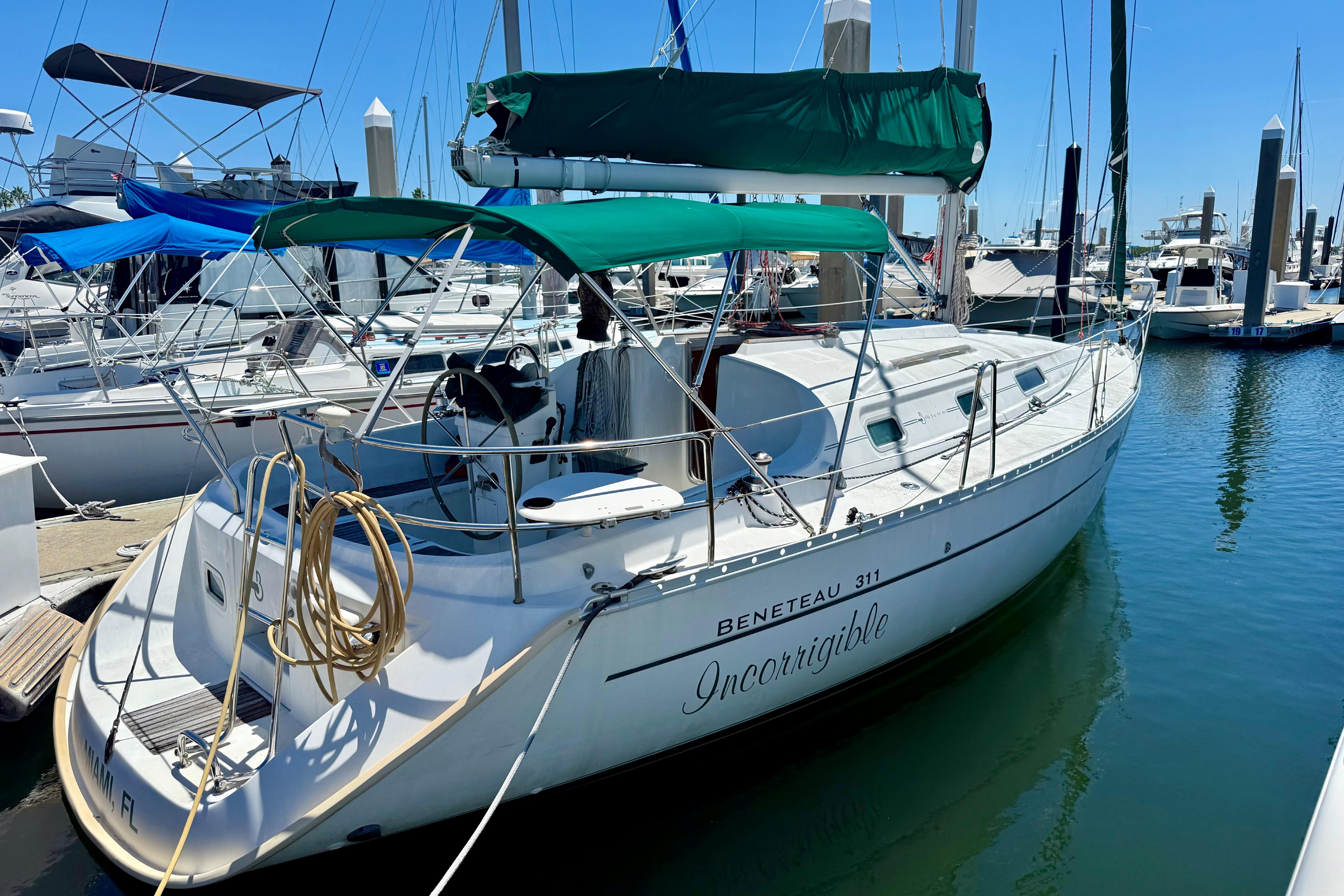 2002 Beneteau Oceanis Clipper 311 sailboat docked in marina, green canopy, sunny day.