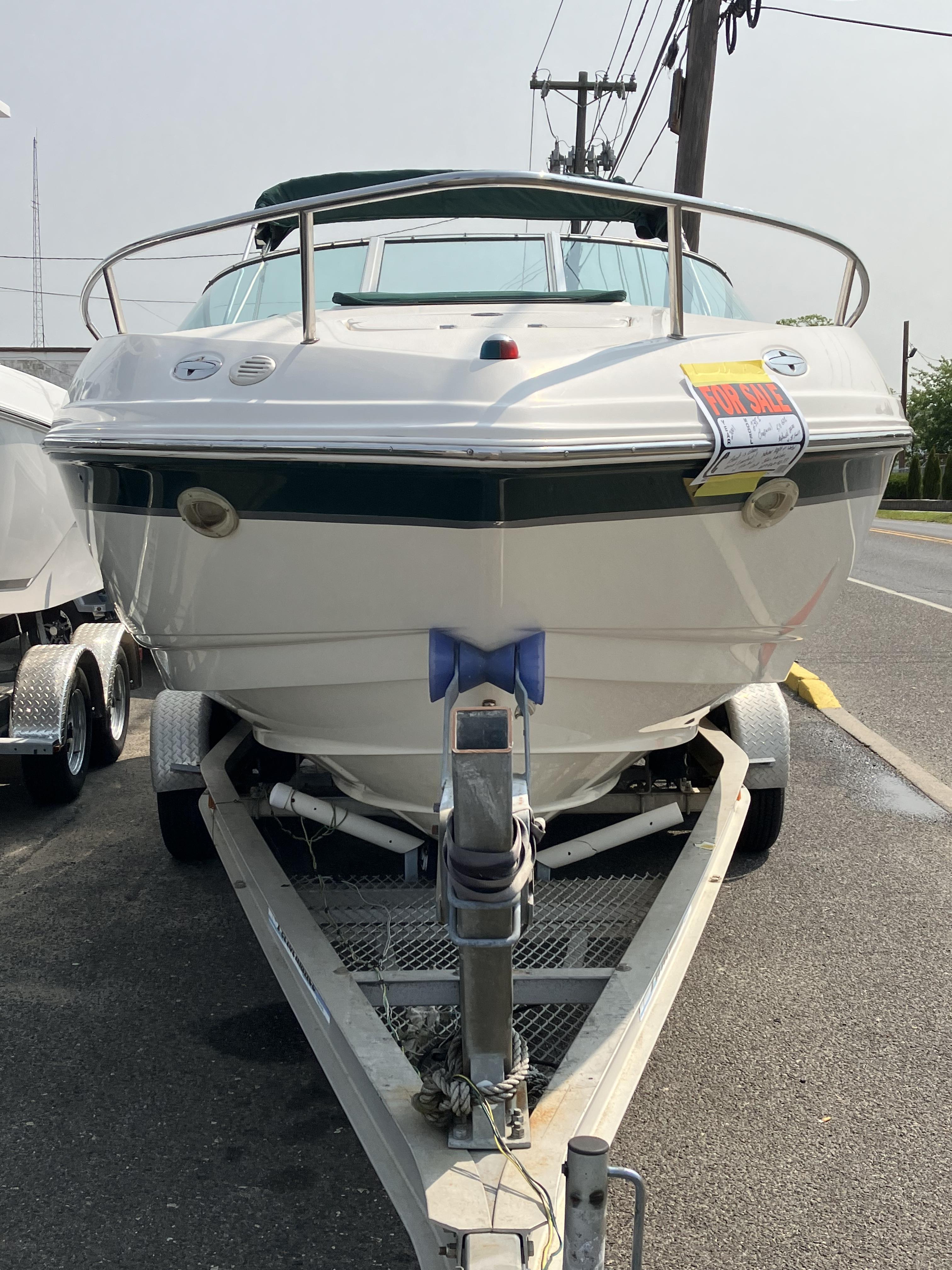 A 2001 Chaparral 235 SSi boat is on a trailer by a roadside.