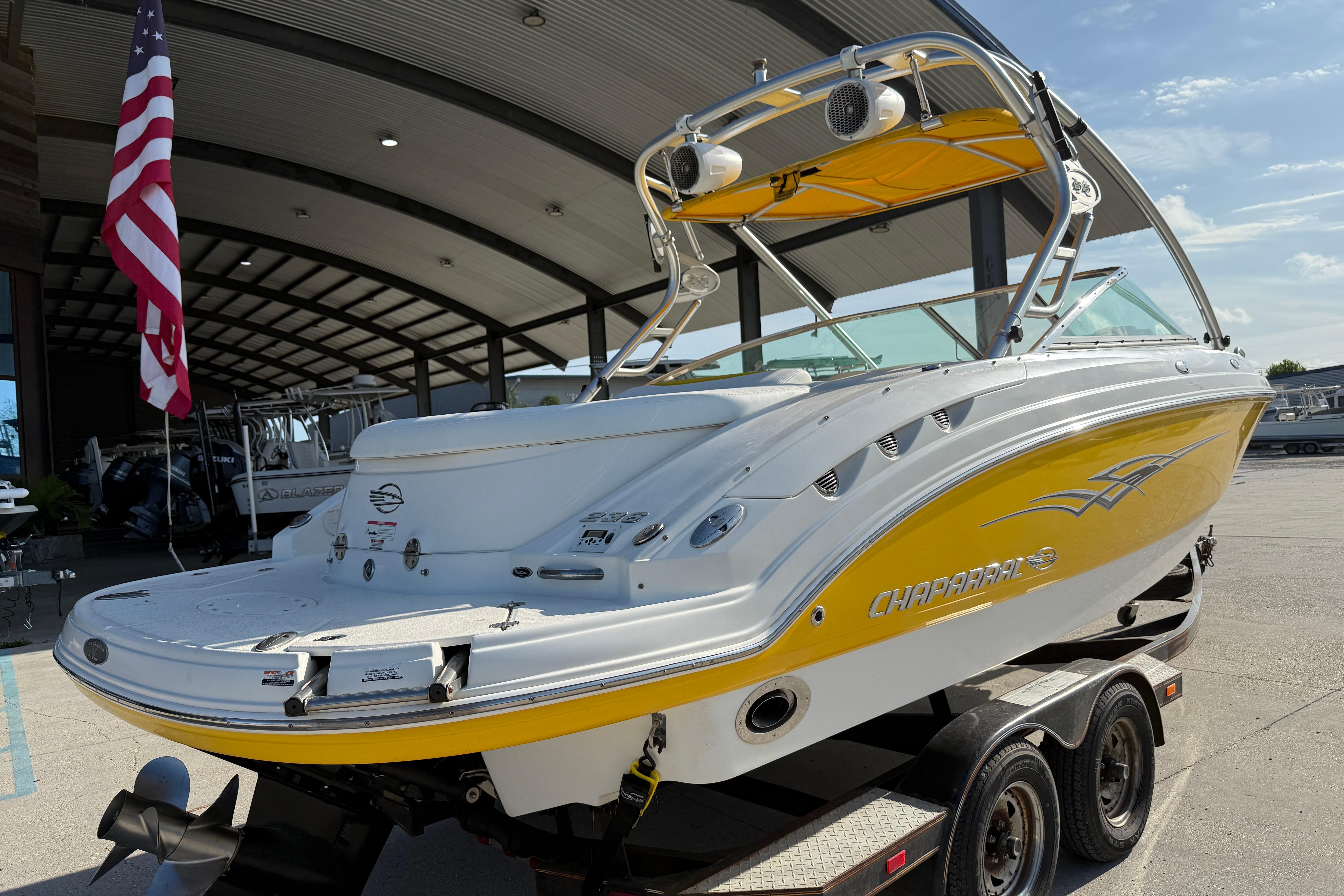 2008 Chaparral 236 SSX boat with yellow accents on a trailer, under a canopy.