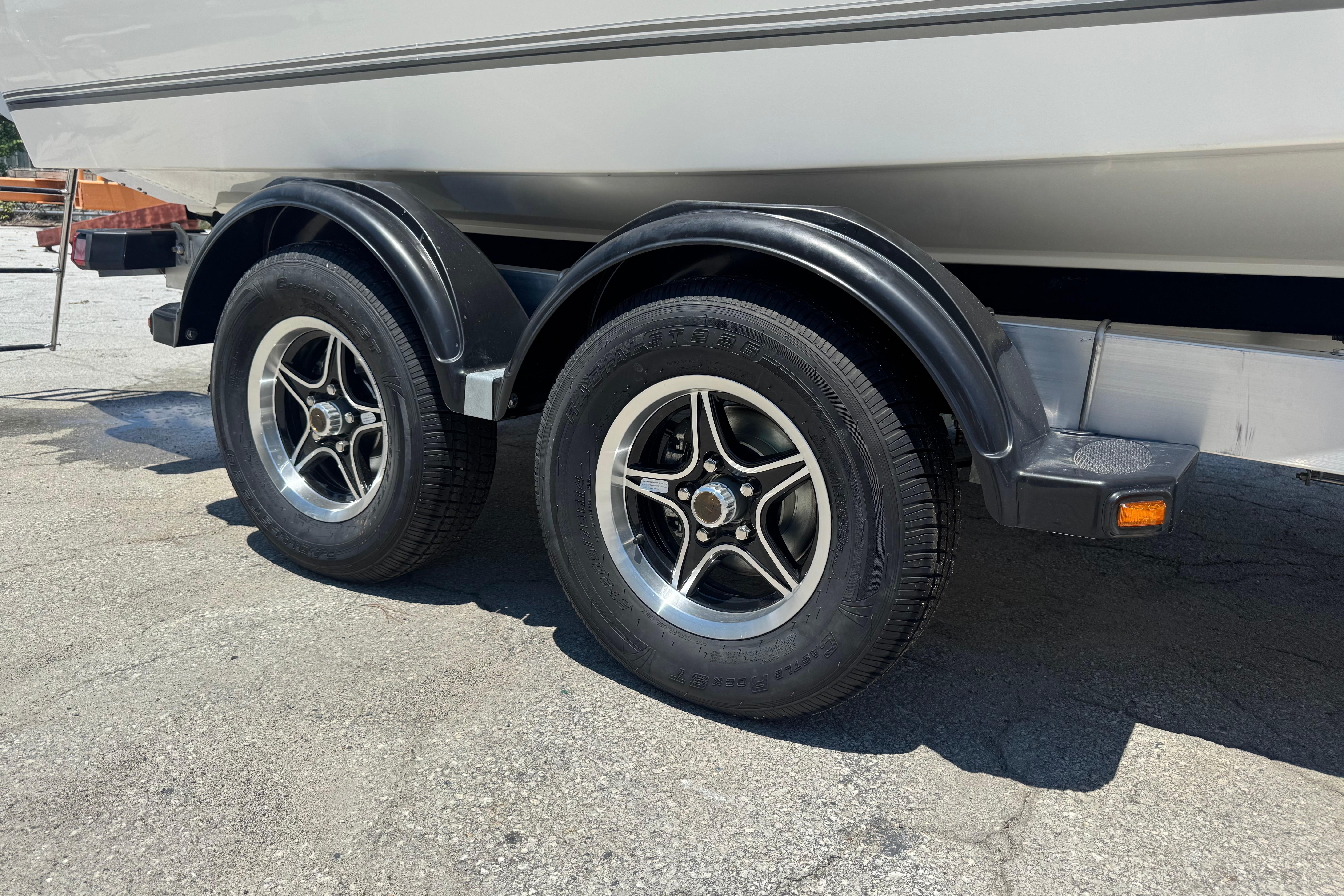 Trailer wheels of a 2026 Mako 214 Center Console boat on pavement.