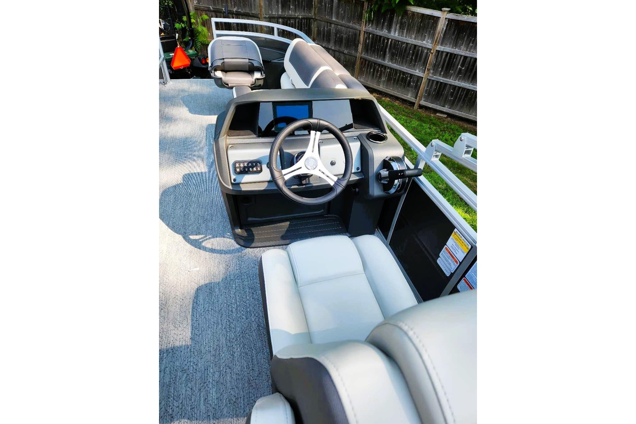 2026 Sun Tracker Fishin' Barge 20 DLX interior with steering wheel and seating.