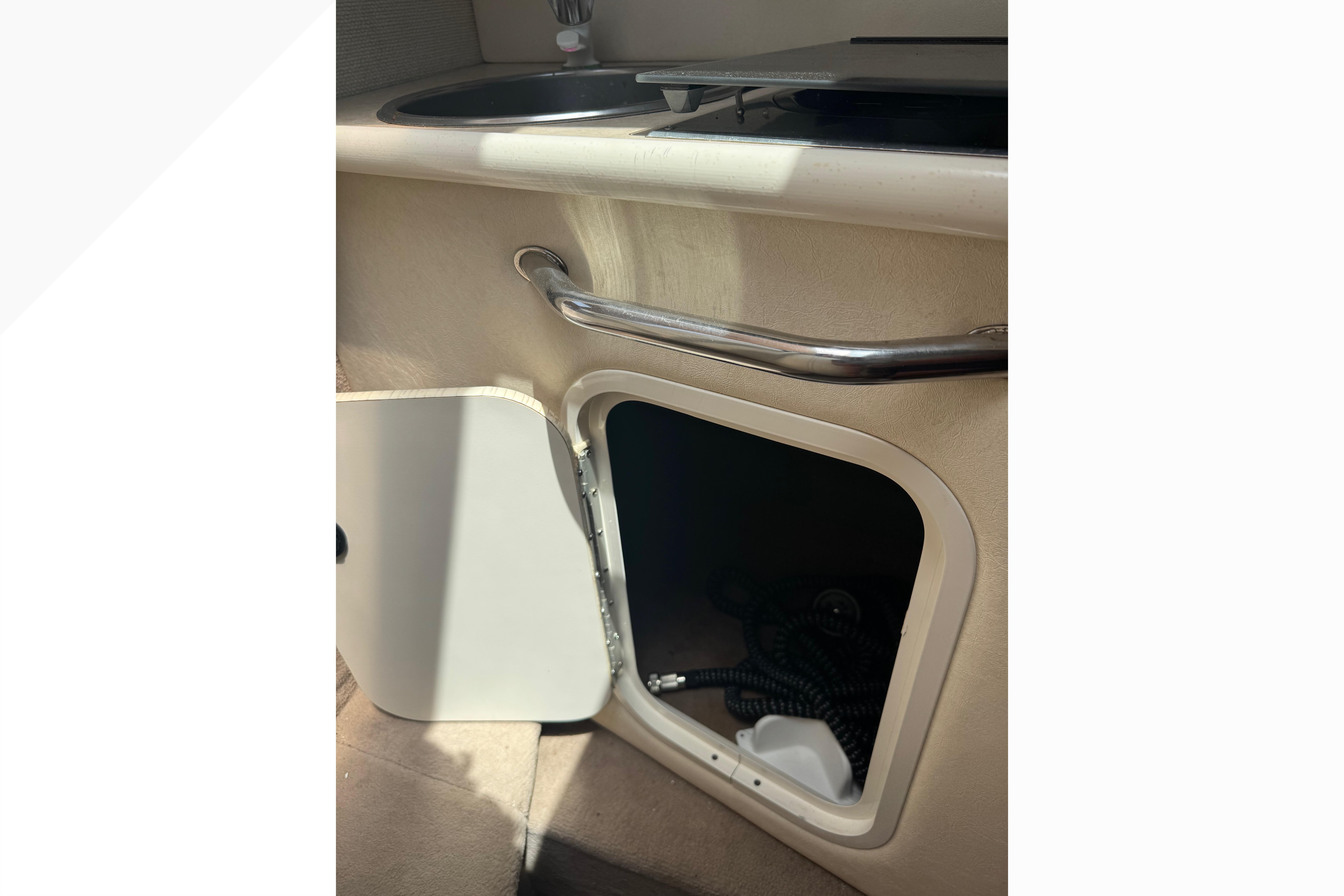 2001 Sea Ray 245 Weekender interior with open storage compartment and sink.