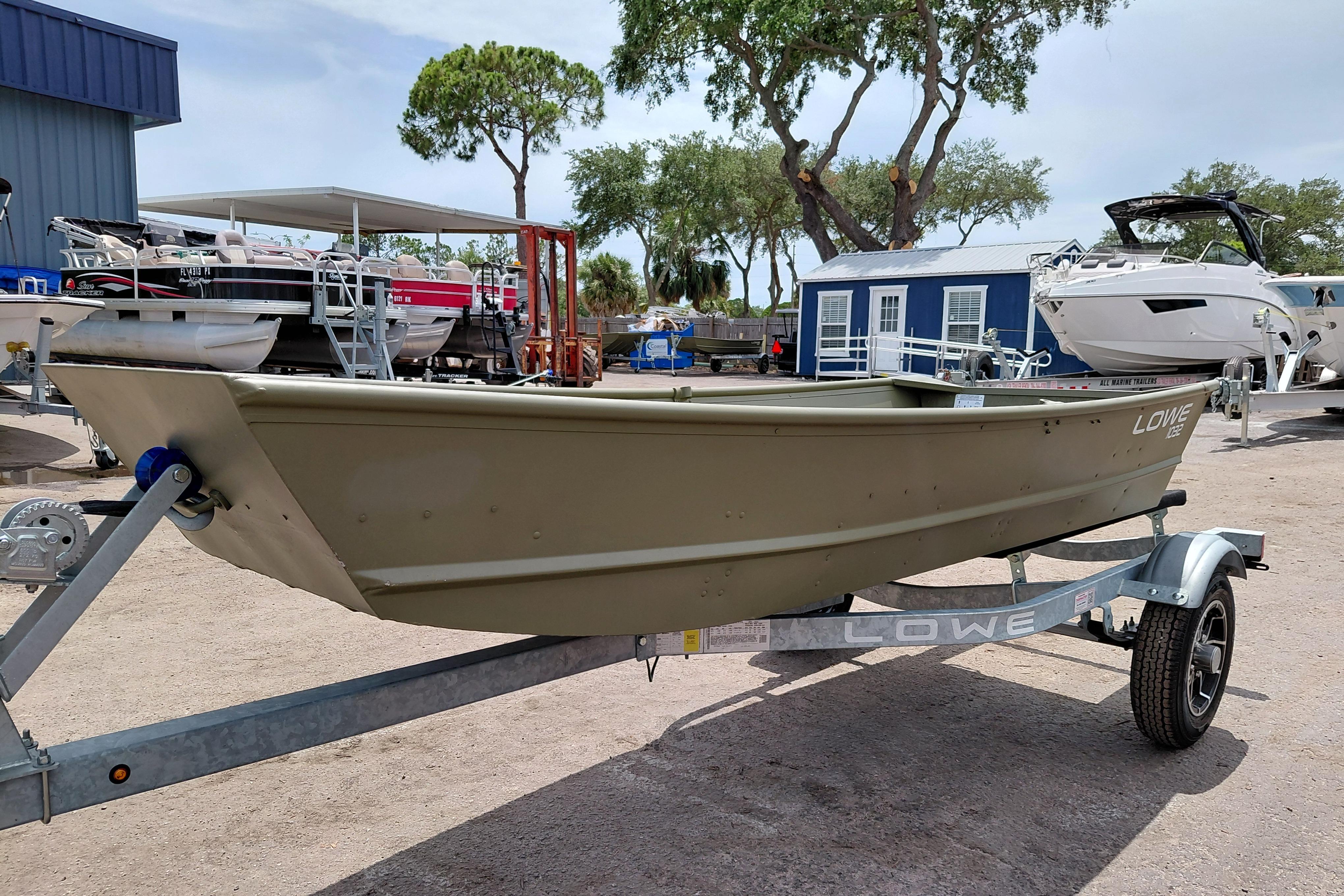 2026 Lowe L1032 Jon boat on trailer, parked outdoors near other boats.