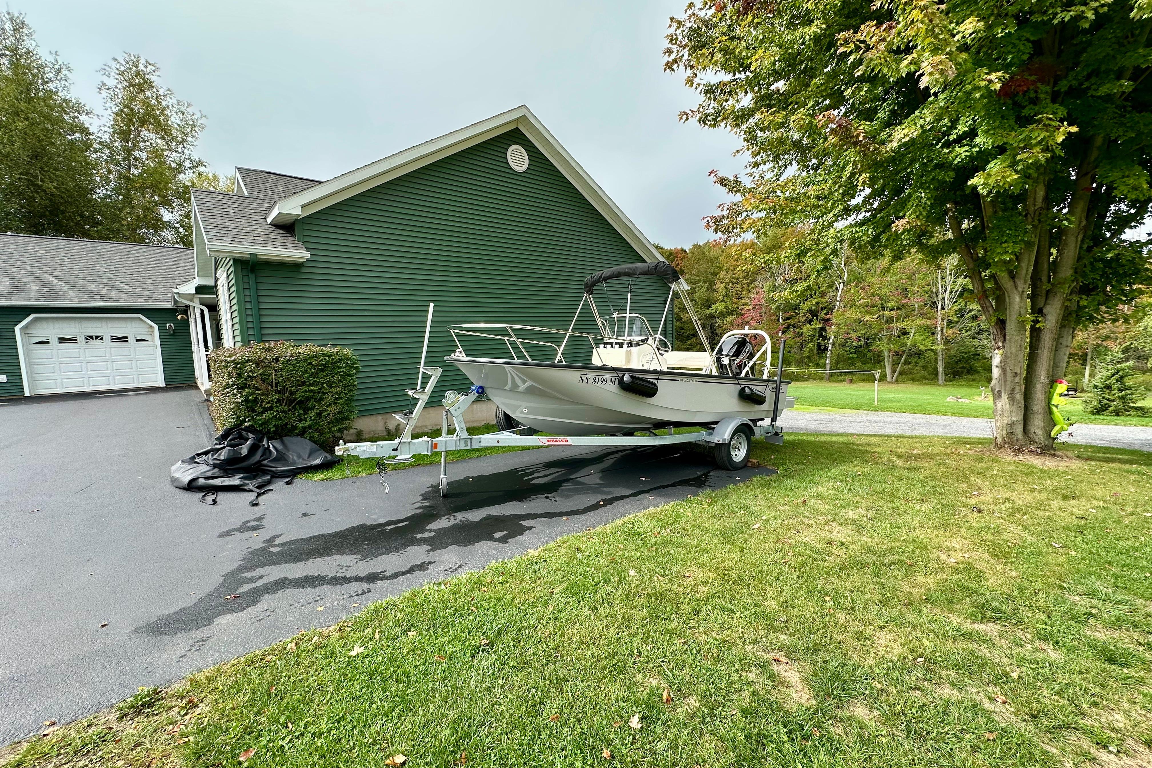 2024 Boston Whaler 170 Montauk boat on trailer beside green house.