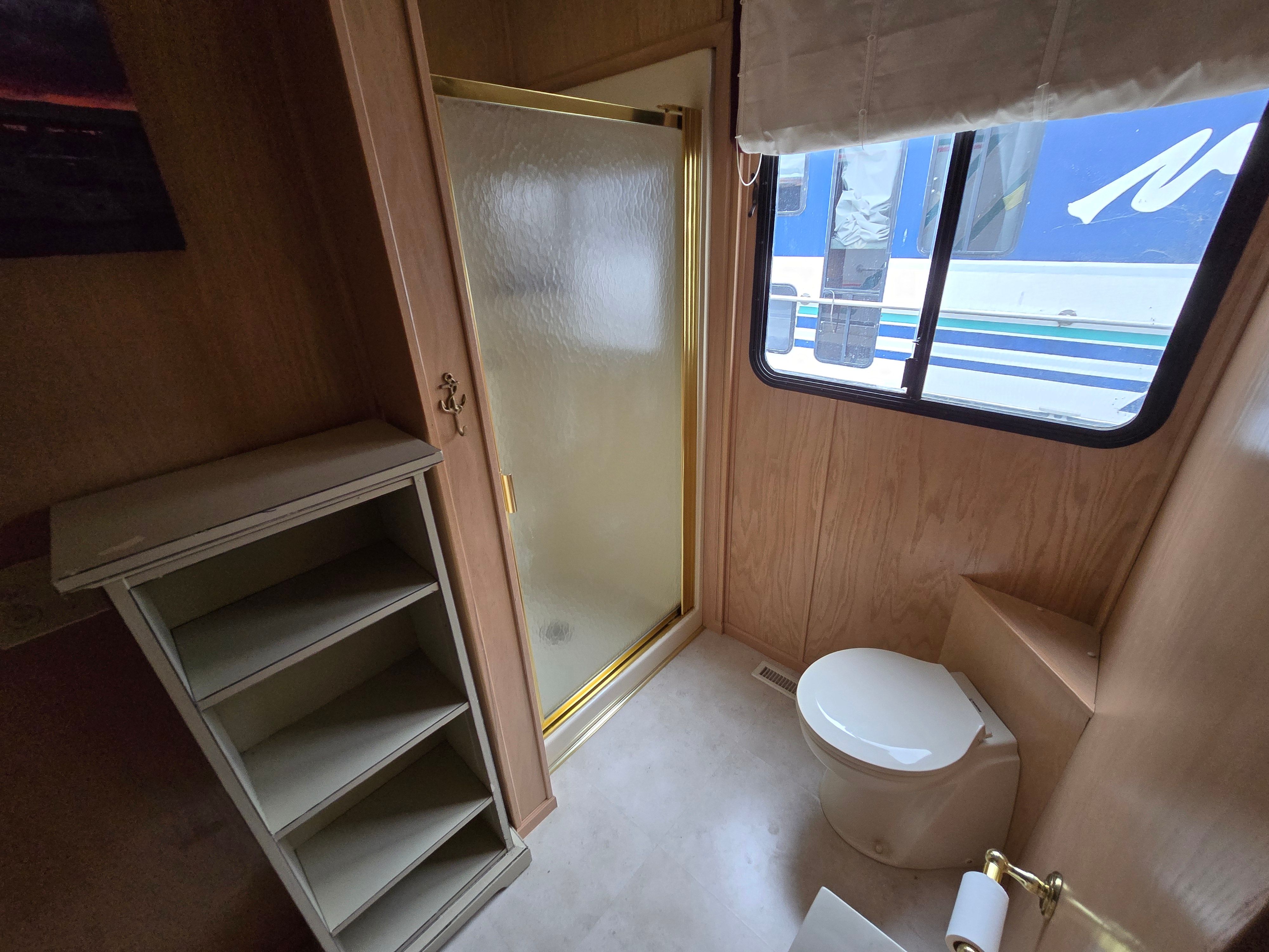 Bathroom interior of a 1998 Sumerset houseboat with shower, toilet, and shelving.