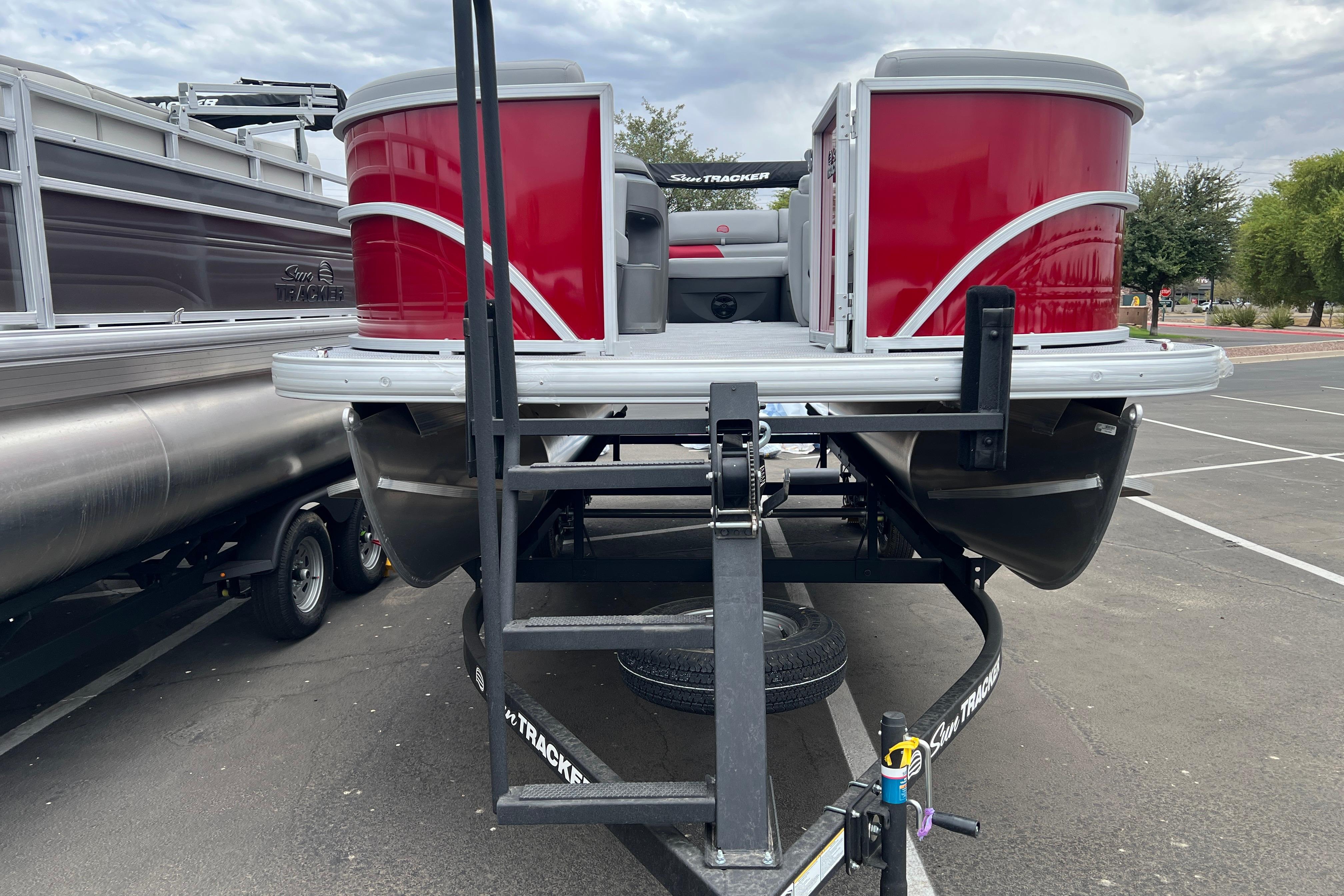 2026 Sun Tracker Party Barge 20 DLX pontoon boat on trailer in parking lot.