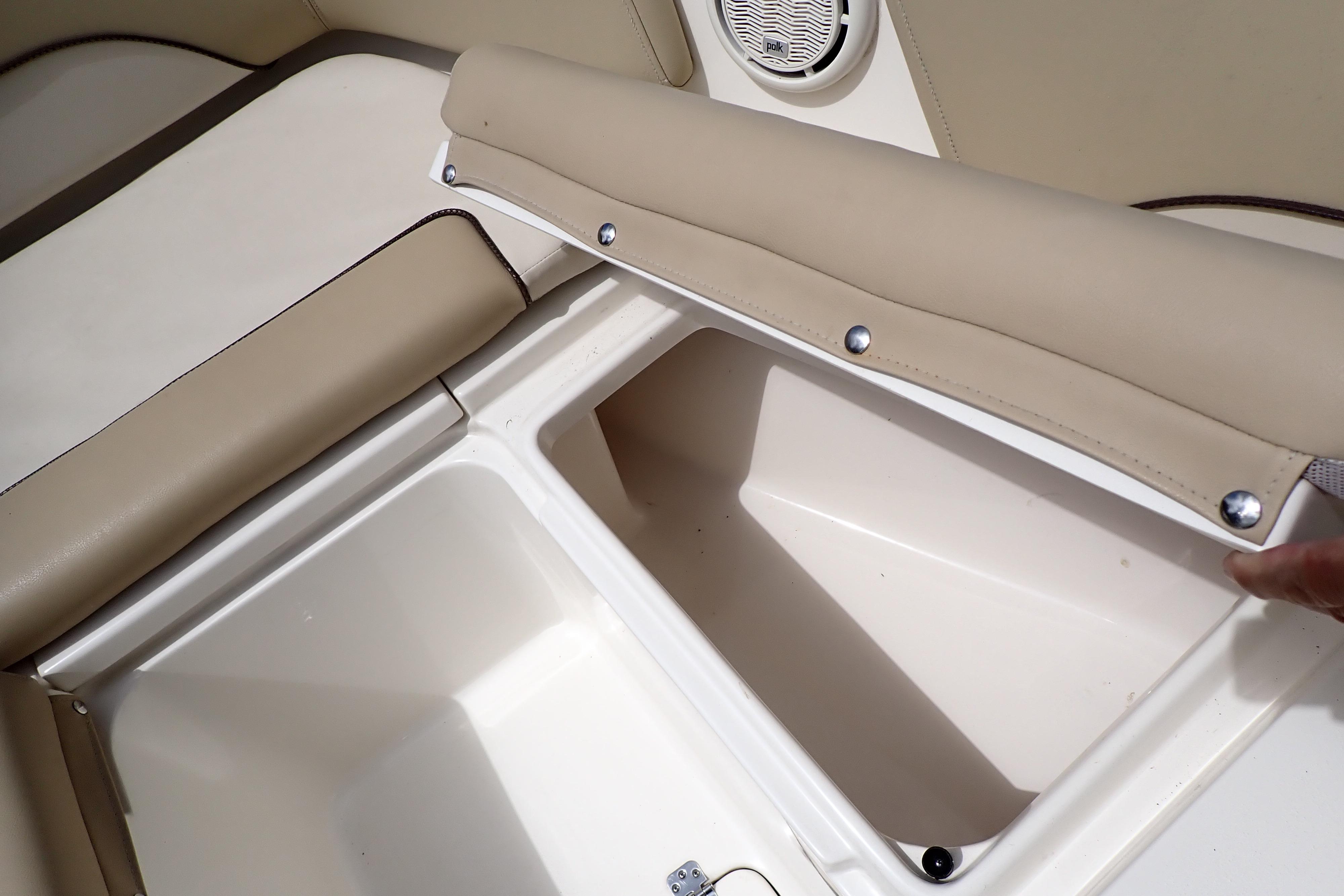 2019 Key West 263 FS boat storage compartment with beige cushioned seating and speaker.
