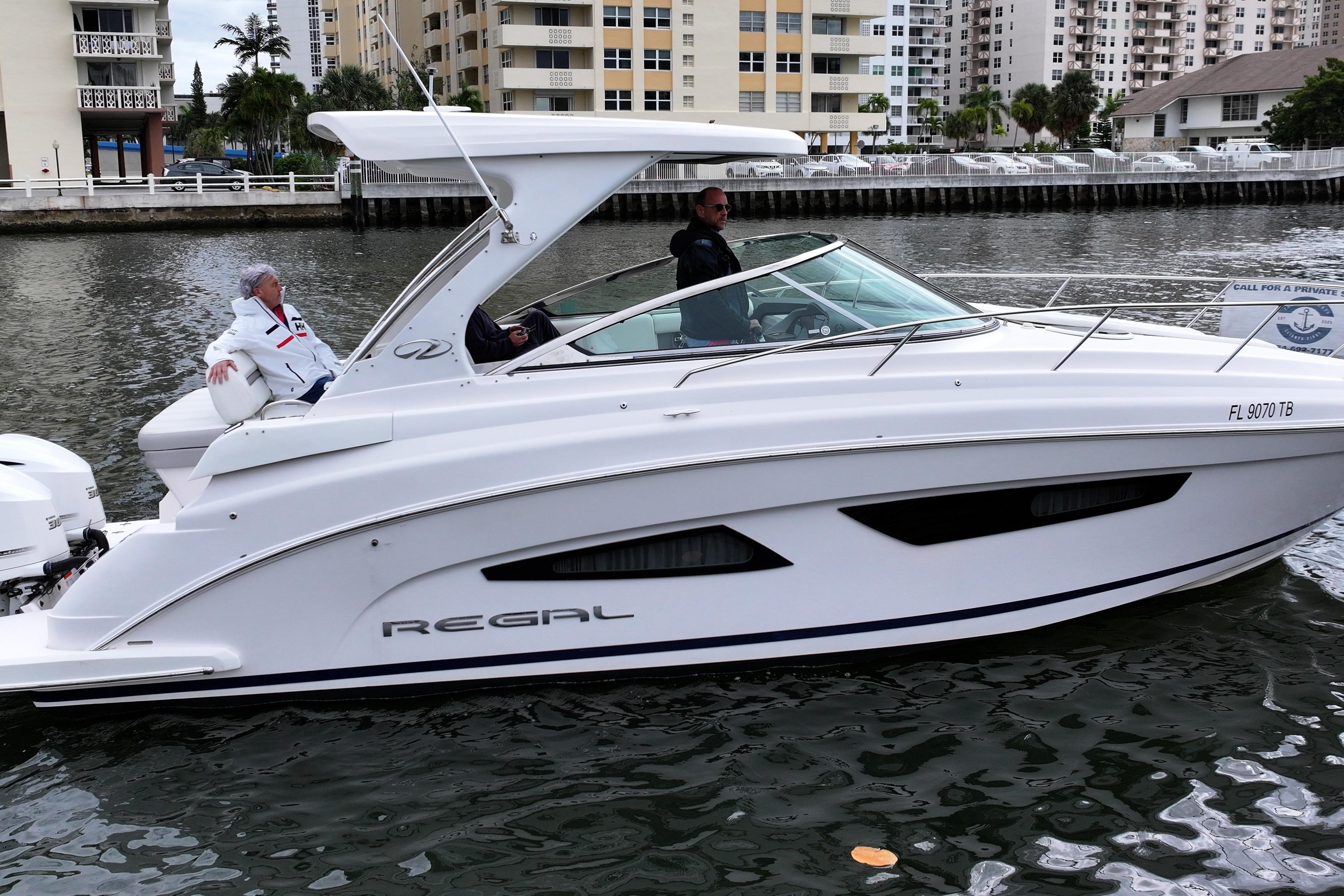 2021 Regal 33 XO boat cruising on a canal with two passengers onboard.