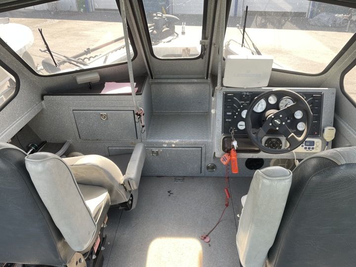 Interior view of a boat with two seats and a helm station.