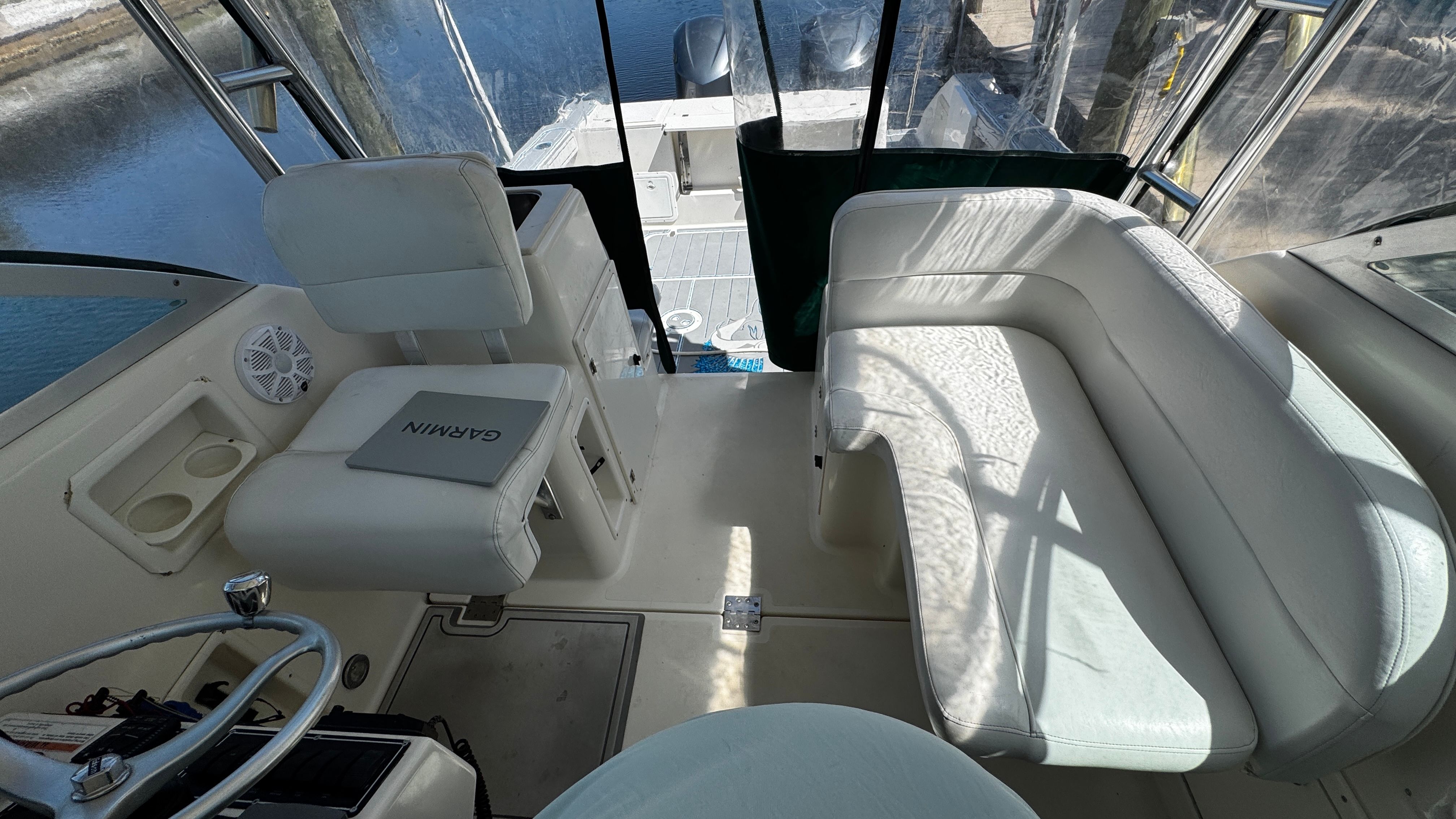 Interior of a 2003 Pursuit 3070 with white seating and a helm station.