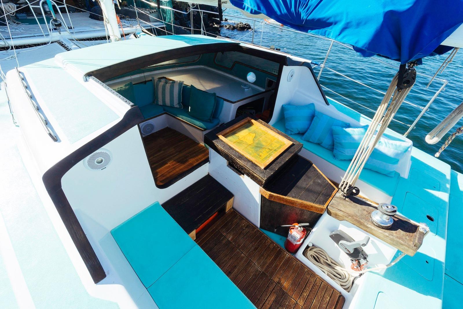 1978 CSK Beach Cat sailboat interior with turquoise seating, wooden flooring, and nautical equipment.