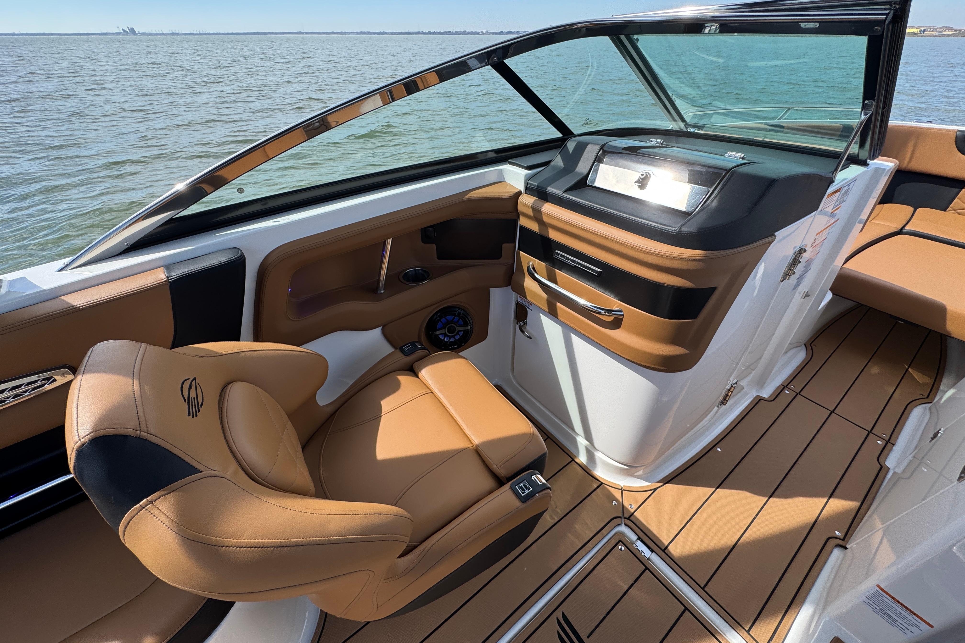 2023 Chaparral 26 Surf boat interior with tan leather seating and sleek dashboard design.