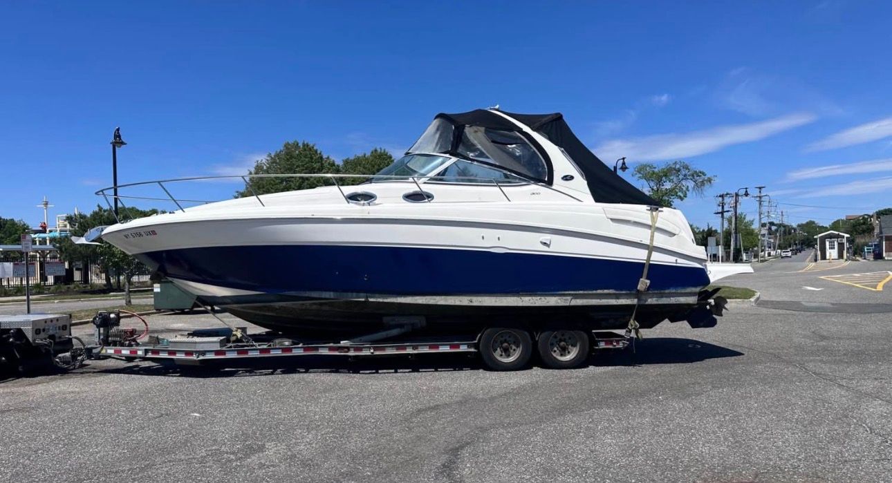 A 2002 Sea Ray 300 Sundancer on a trailer, parked on land.
