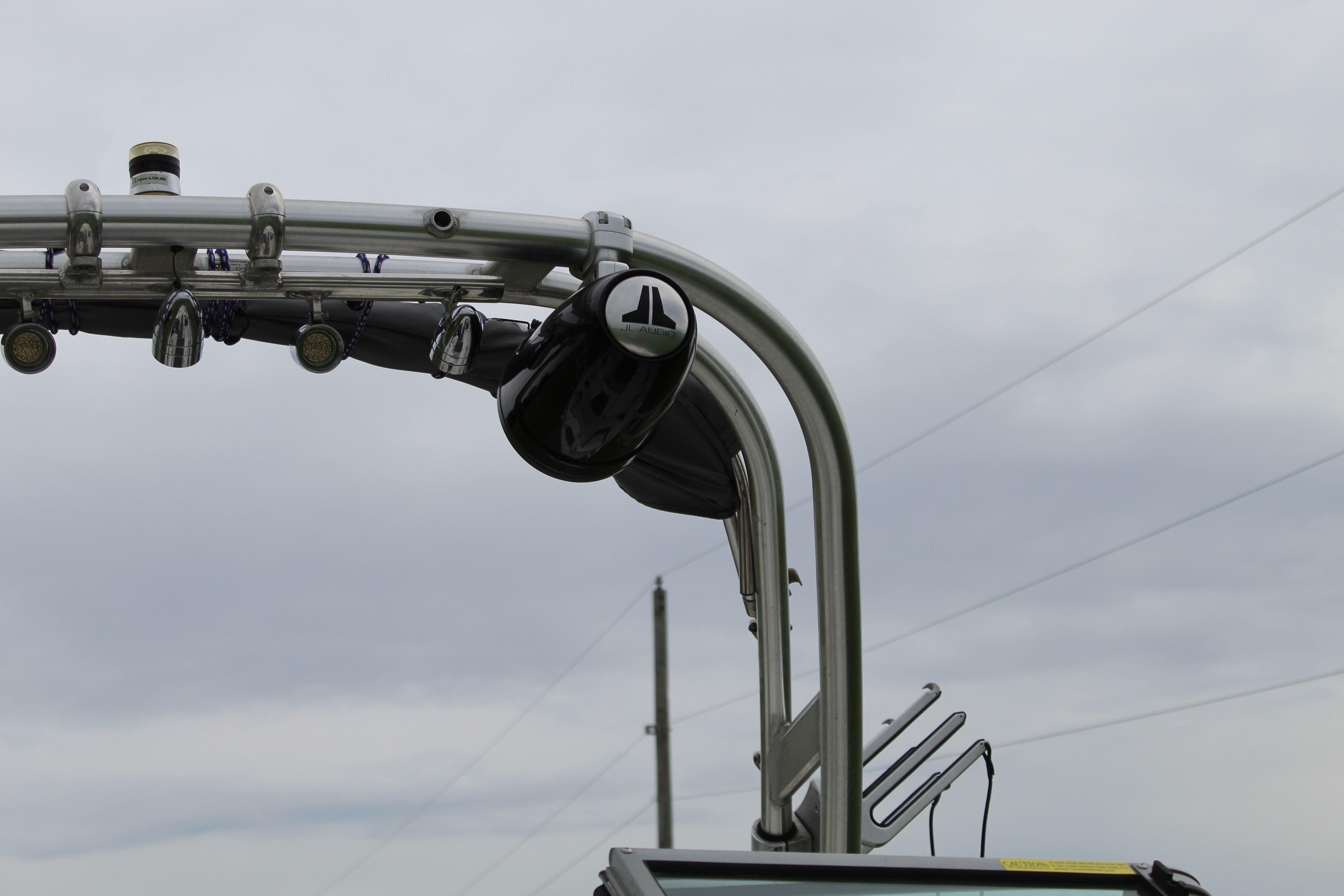 Close-up of a boat tower with speakers and lights under a cloudy sky.