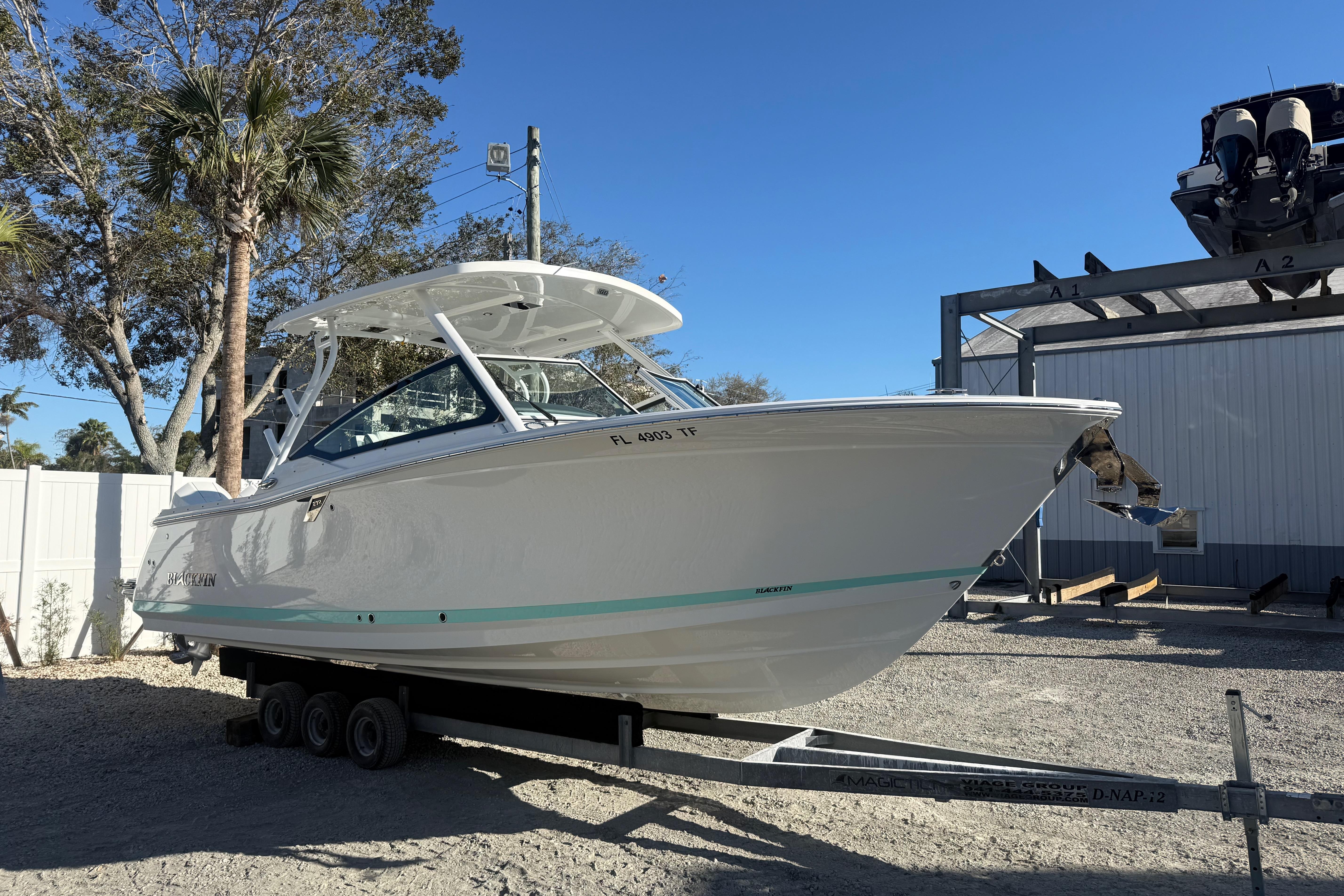 2022 Blackfin 272 DC boat on trailer, parked outdoors under clear blue sky.