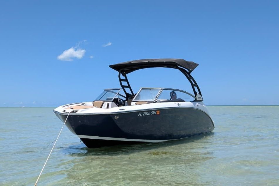 A 2021 Yamaha 252SD boat anchored in clear, shallow water under a blue sky.