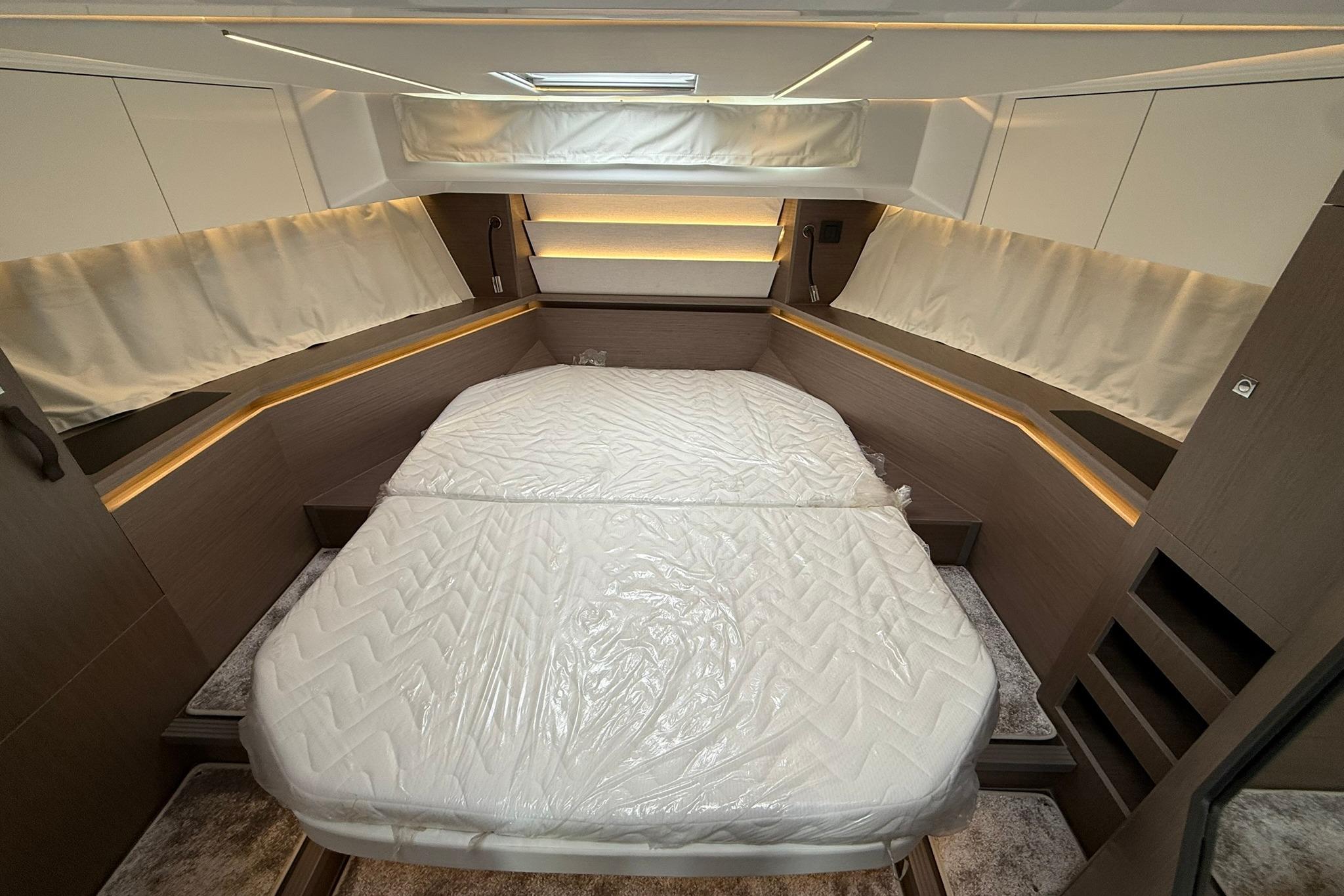 Luxurious cabin interior of 2026 Jeanneau NC 1295 Coupe with cozy bedding.