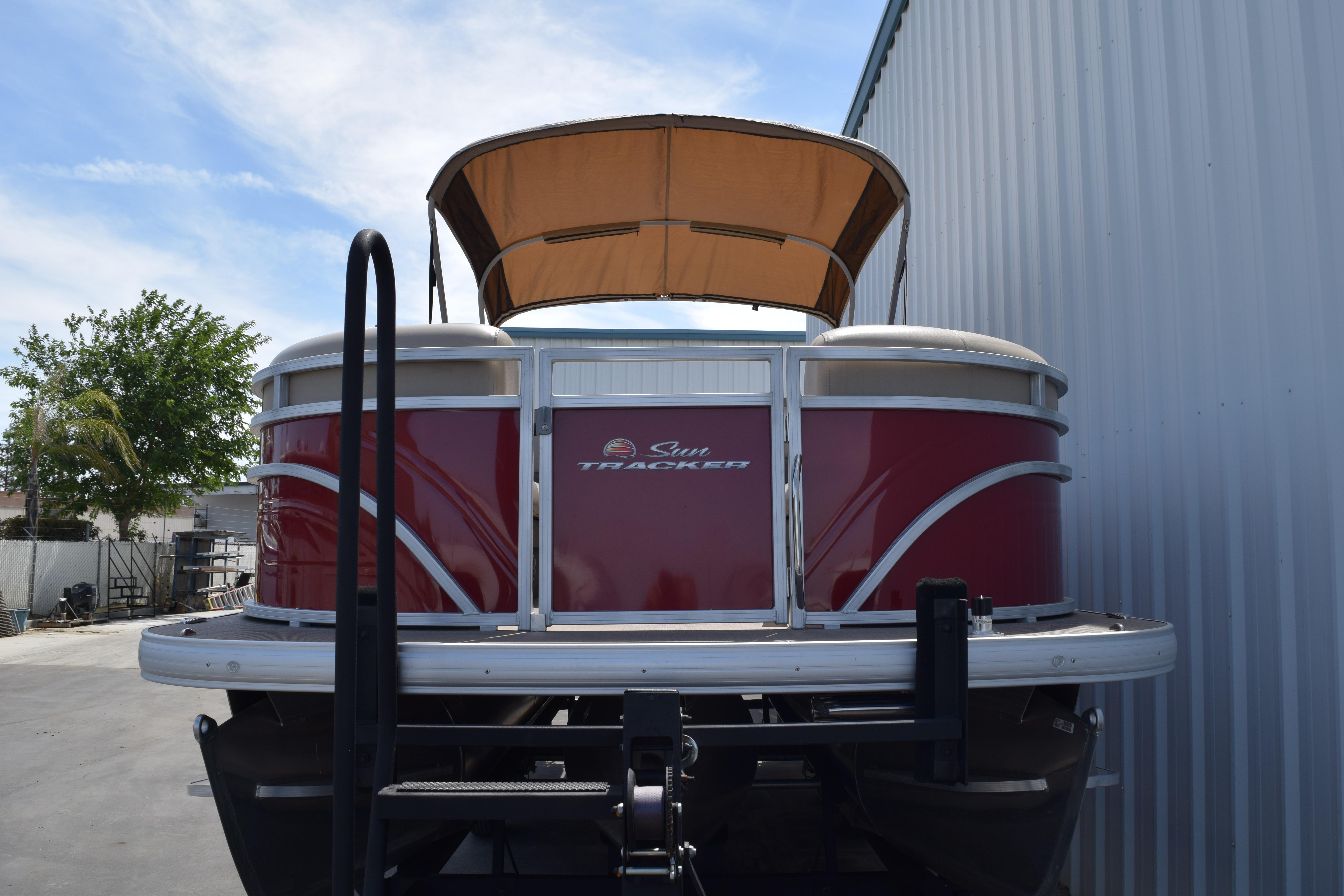2025 Sun Tracker Party Barge 22 XP3 pontoon boat with canopy, parked outdoors.