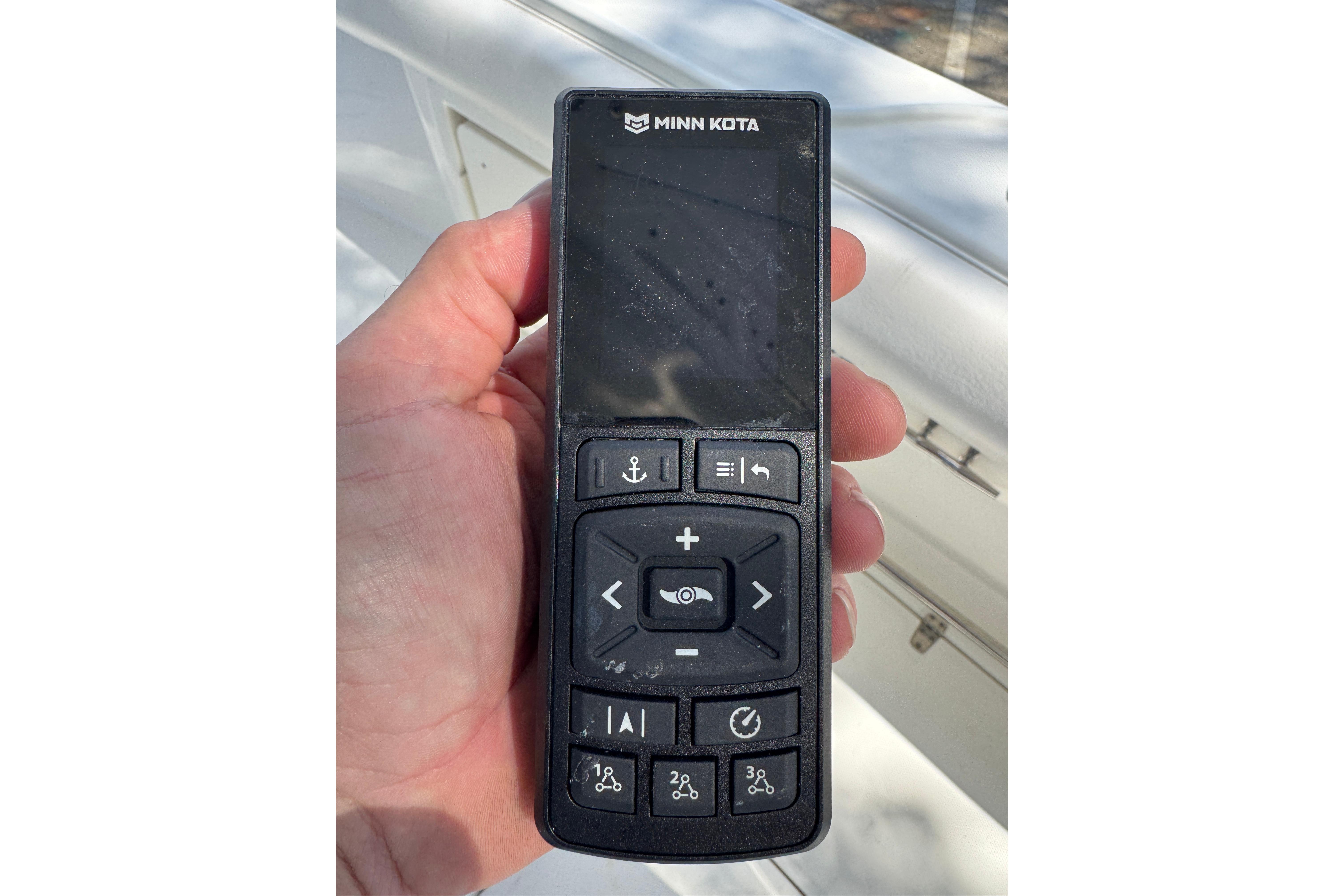 Hand holding Minn Kota remote control on a 2014 Boston Whaler 250 Outrage boat.