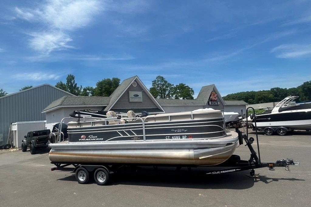 2023 Sun Tracker Party Barge 22 DLX pontoon boat on trailer at dealership.