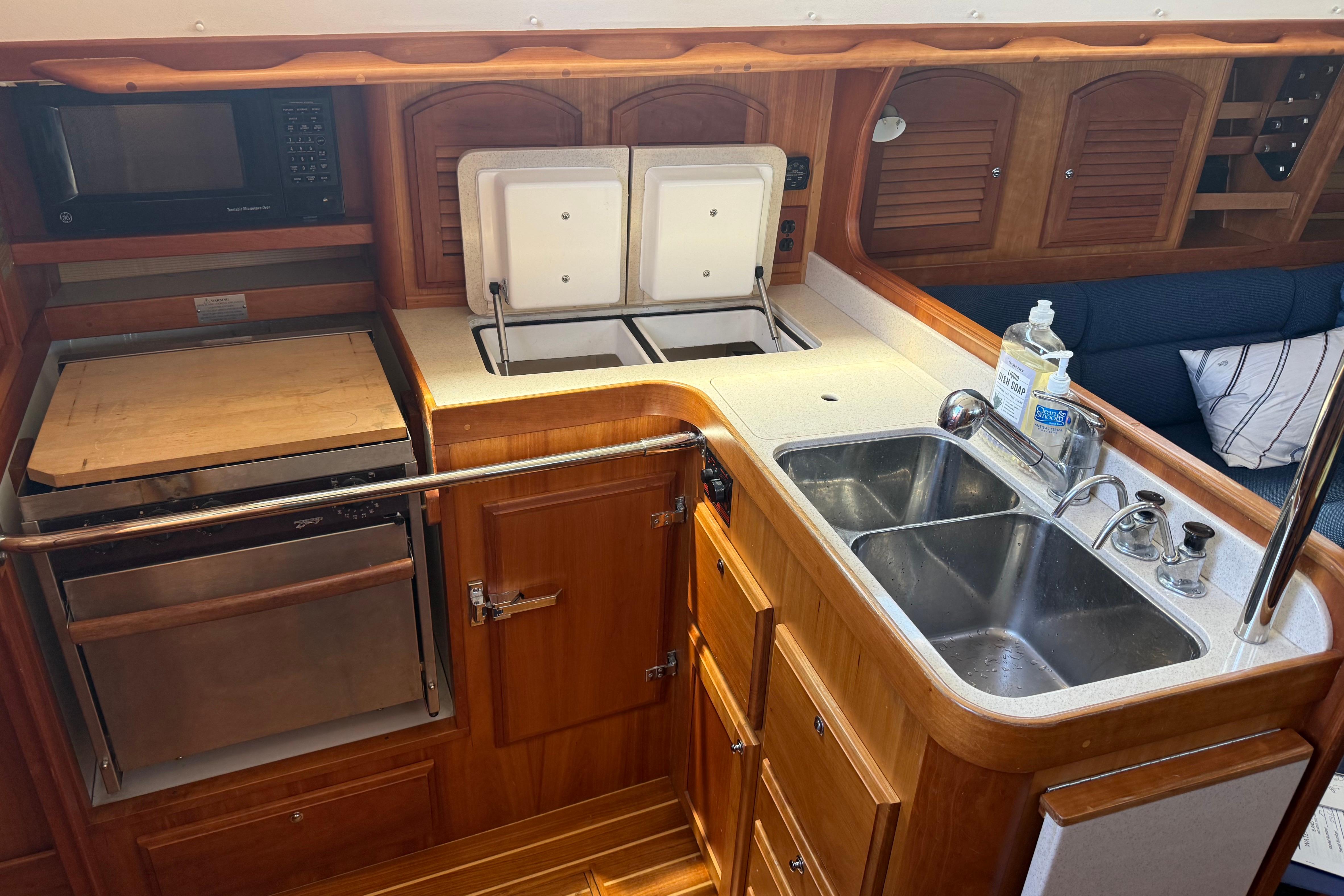 2004 Sabre 386 yacht kitchen with dual sinks, microwave, and wooden cabinetry.