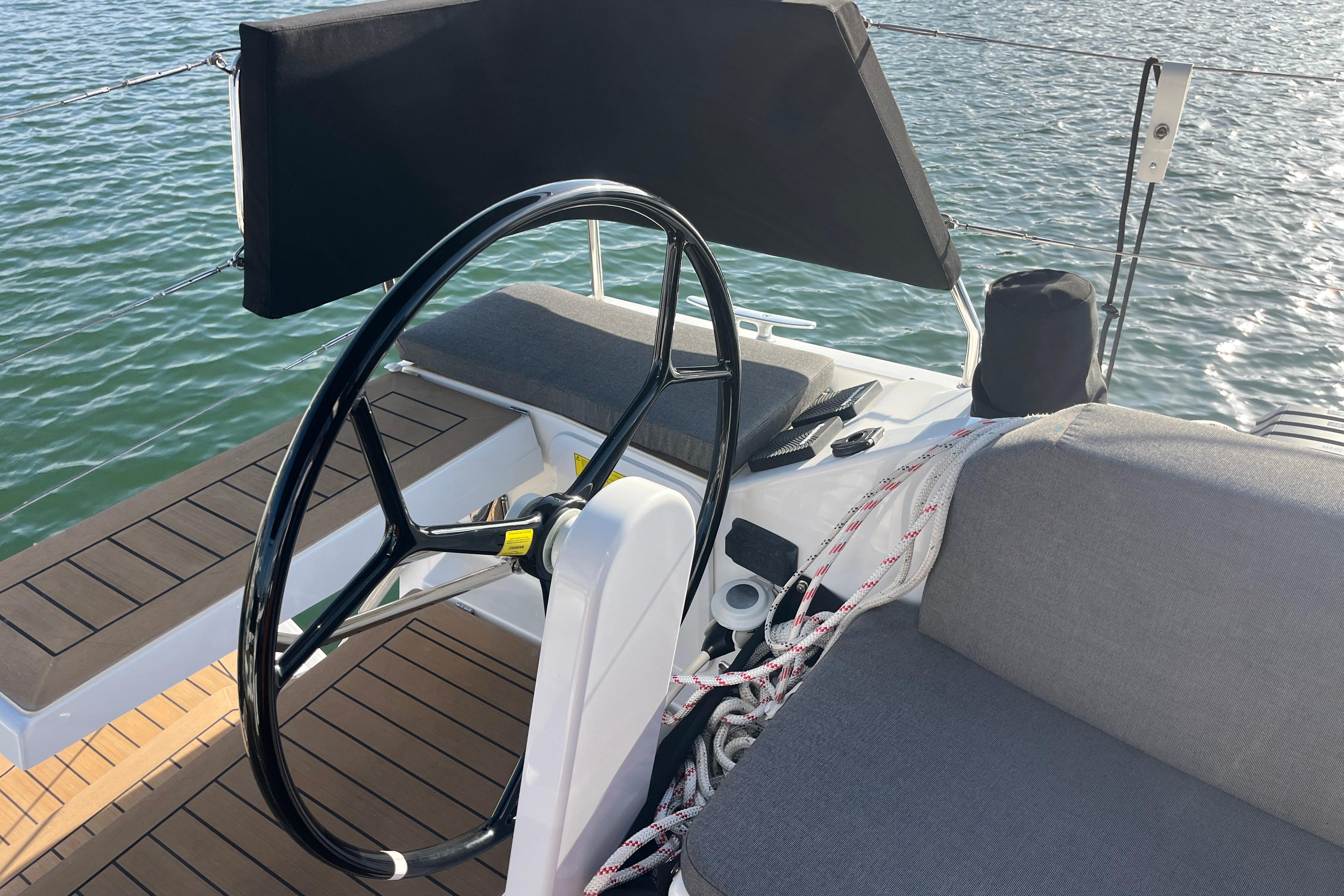 2025 Hanse 360 yacht cockpit with steering wheel and seating, overlooking calm waters.
