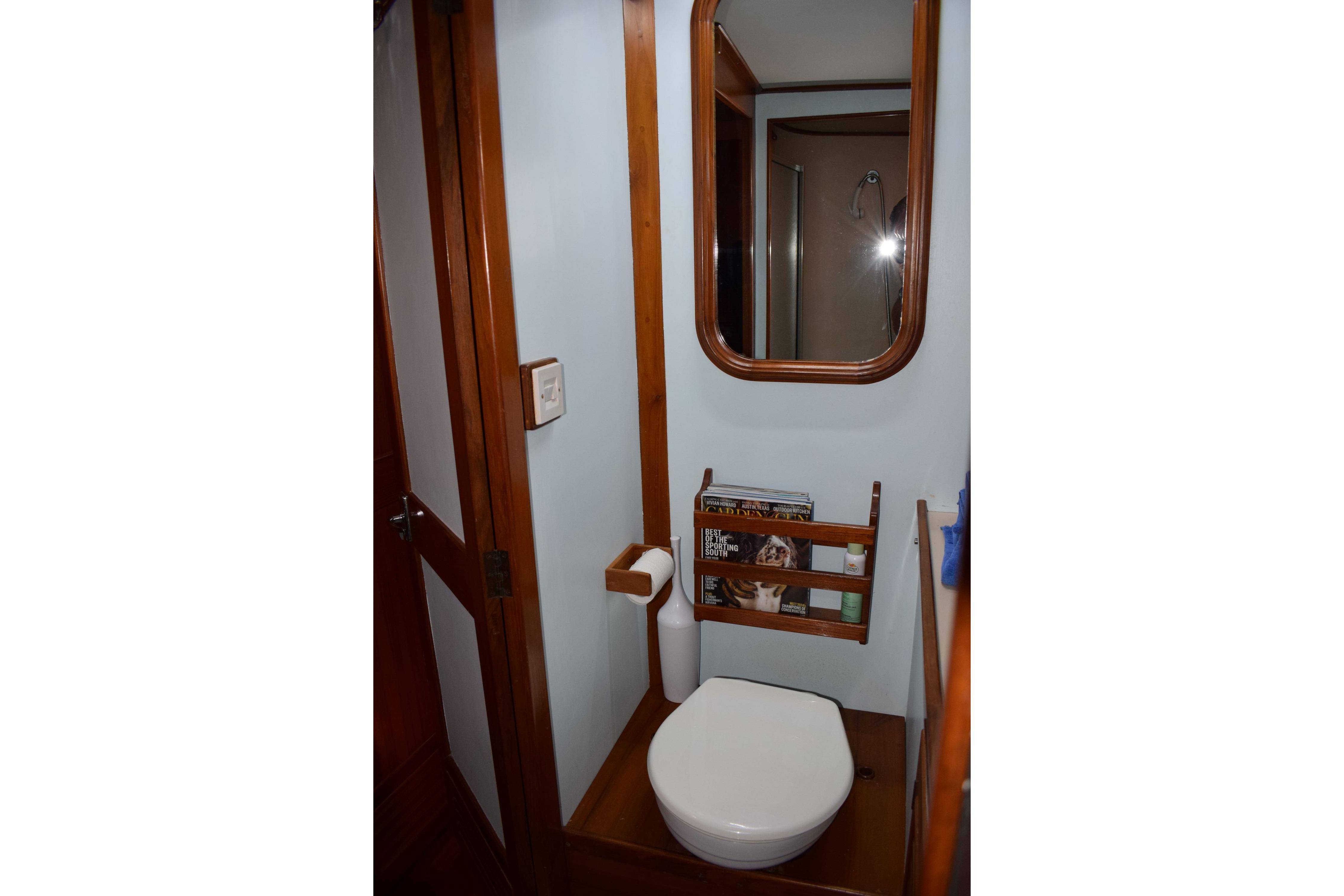 Compact bathroom in 1980 Cheoy Lee 52 Motorsailer with wooden accents and mirror.