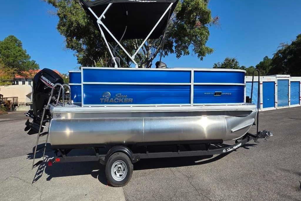 2026 Sun Tracker Party Barge 18 DLX pontoon boat with blue exterior, parked outdoors.