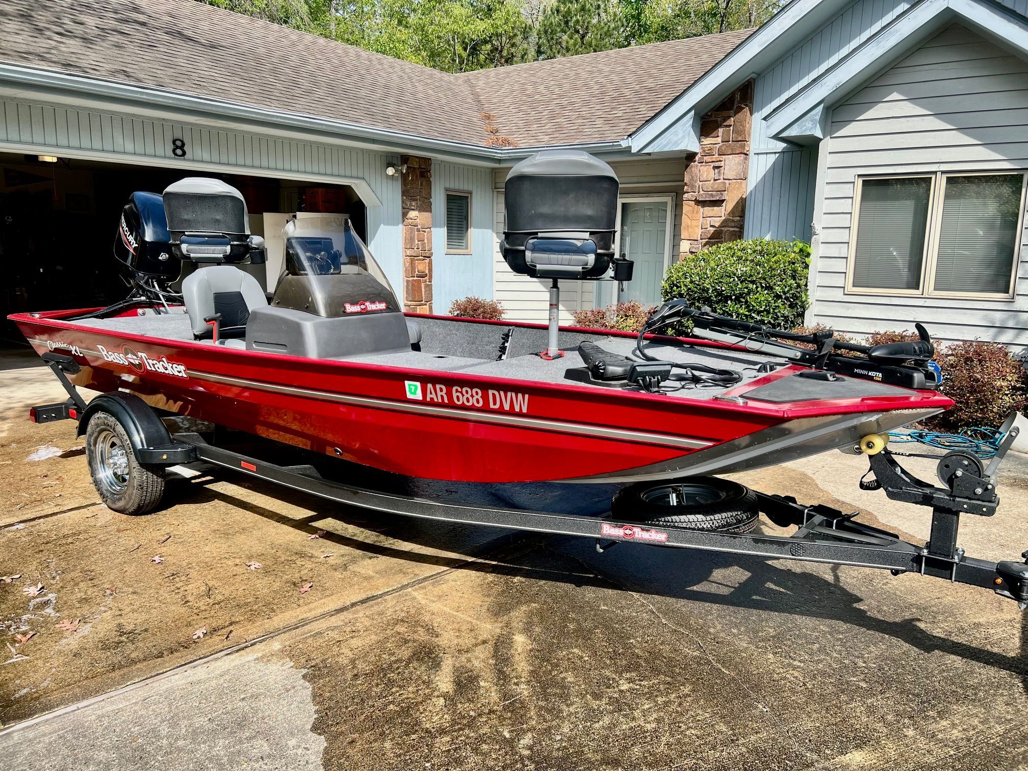 Red 2022 Bass Tracker Classic XL boat on trailer in front of house.