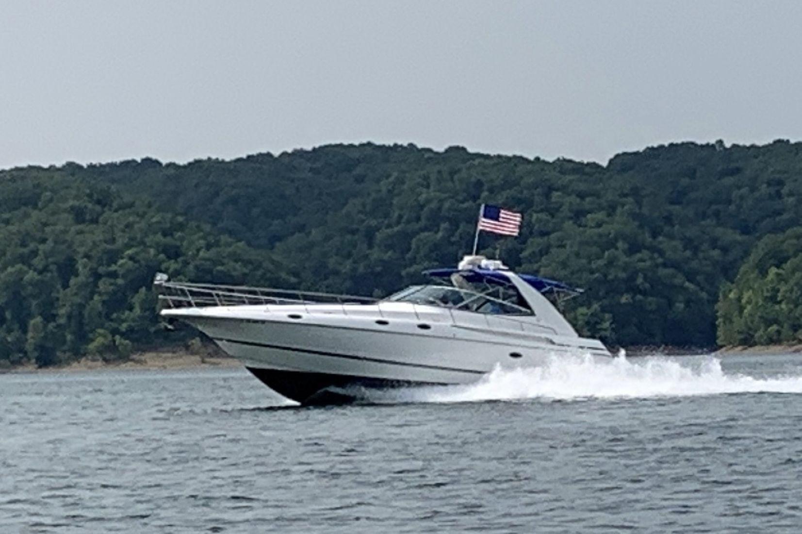 2000 Cruisers Yachts 4270 Express cruising on a lake with forested hills in the background.