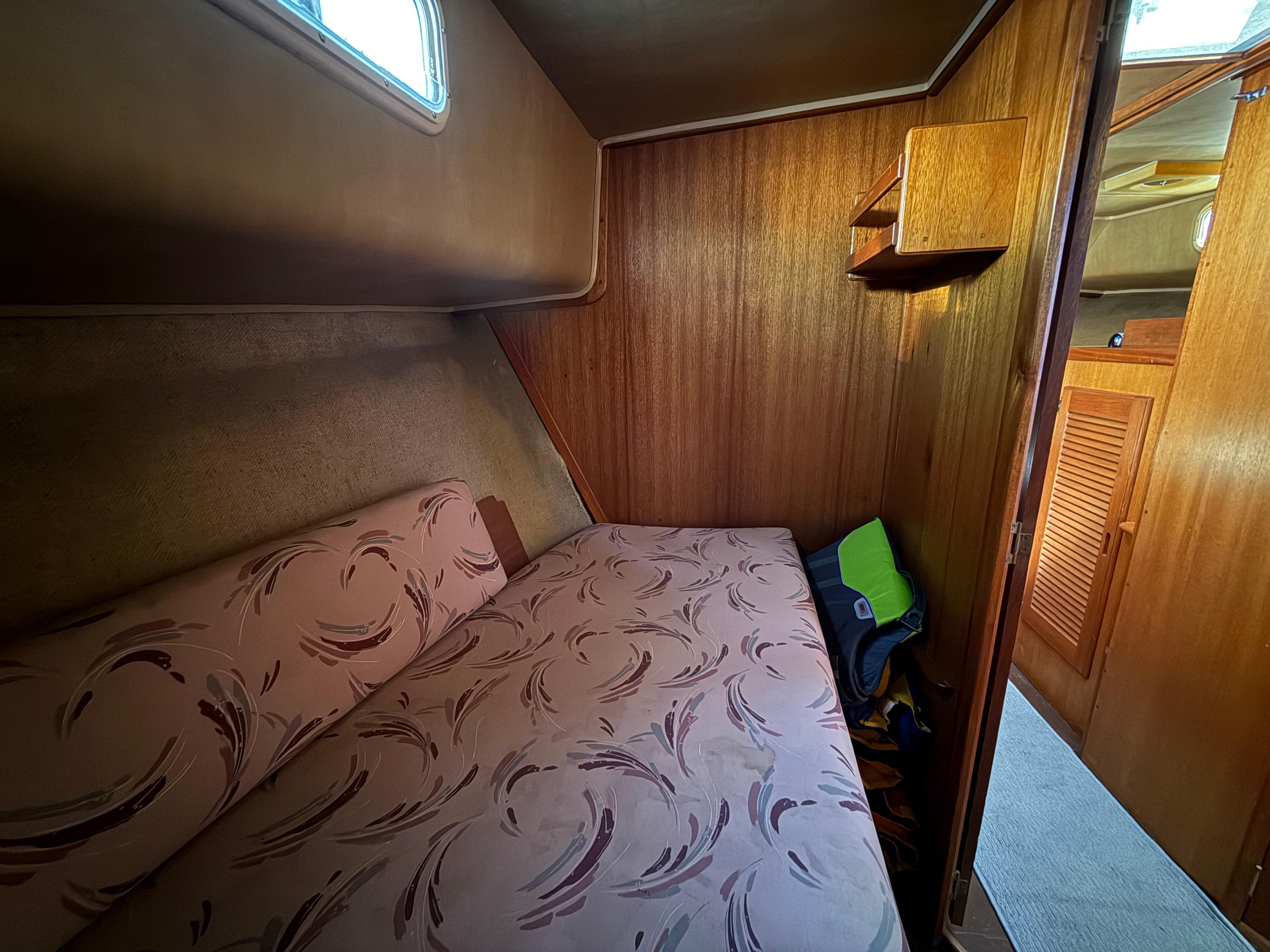 Cozy cabin interior of 1983 Californian 34 boat with patterned bedding and wooden walls.