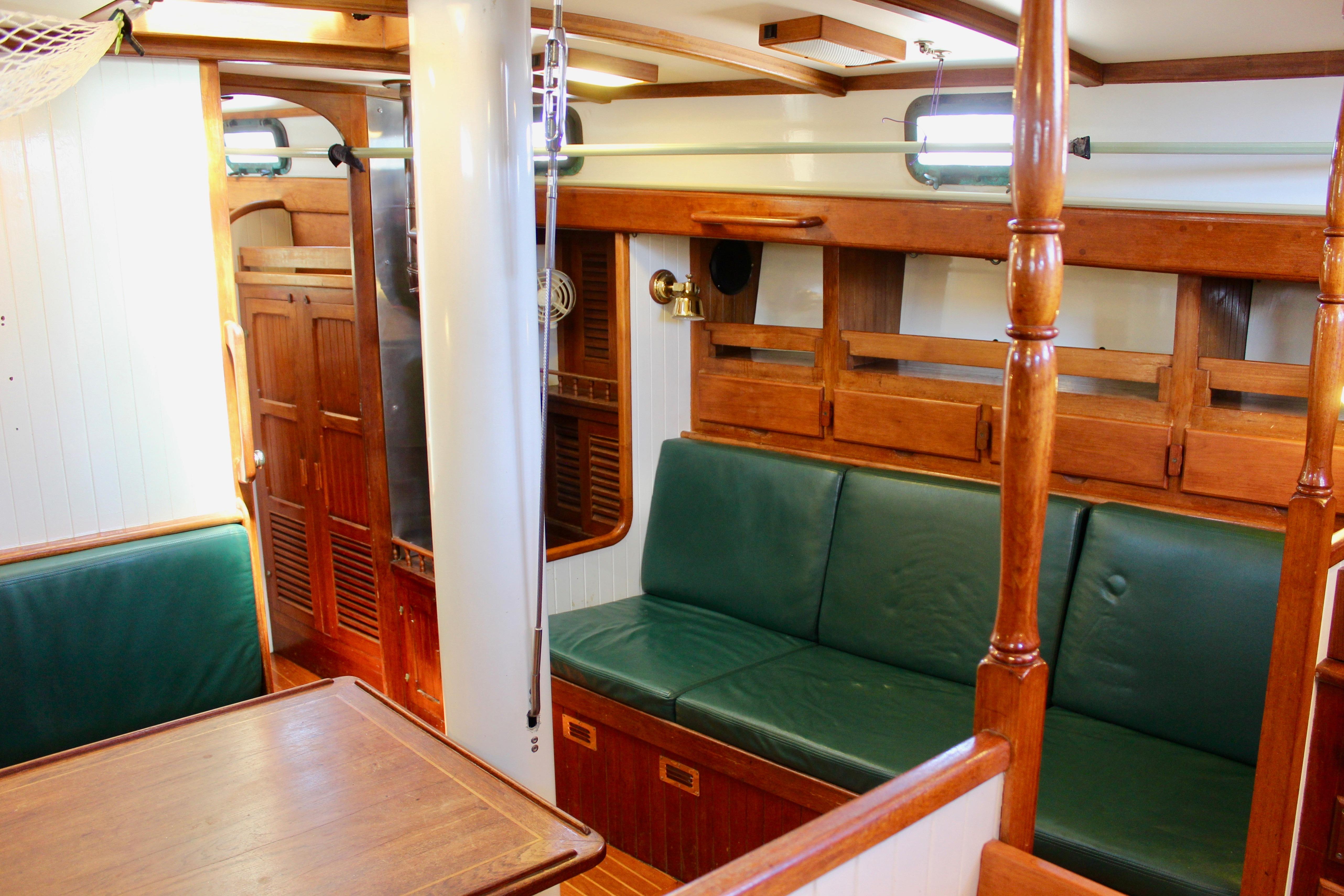 Interior of 1981 Kelly Peterson 46 sailboat with wooden furnishings and green seating.
