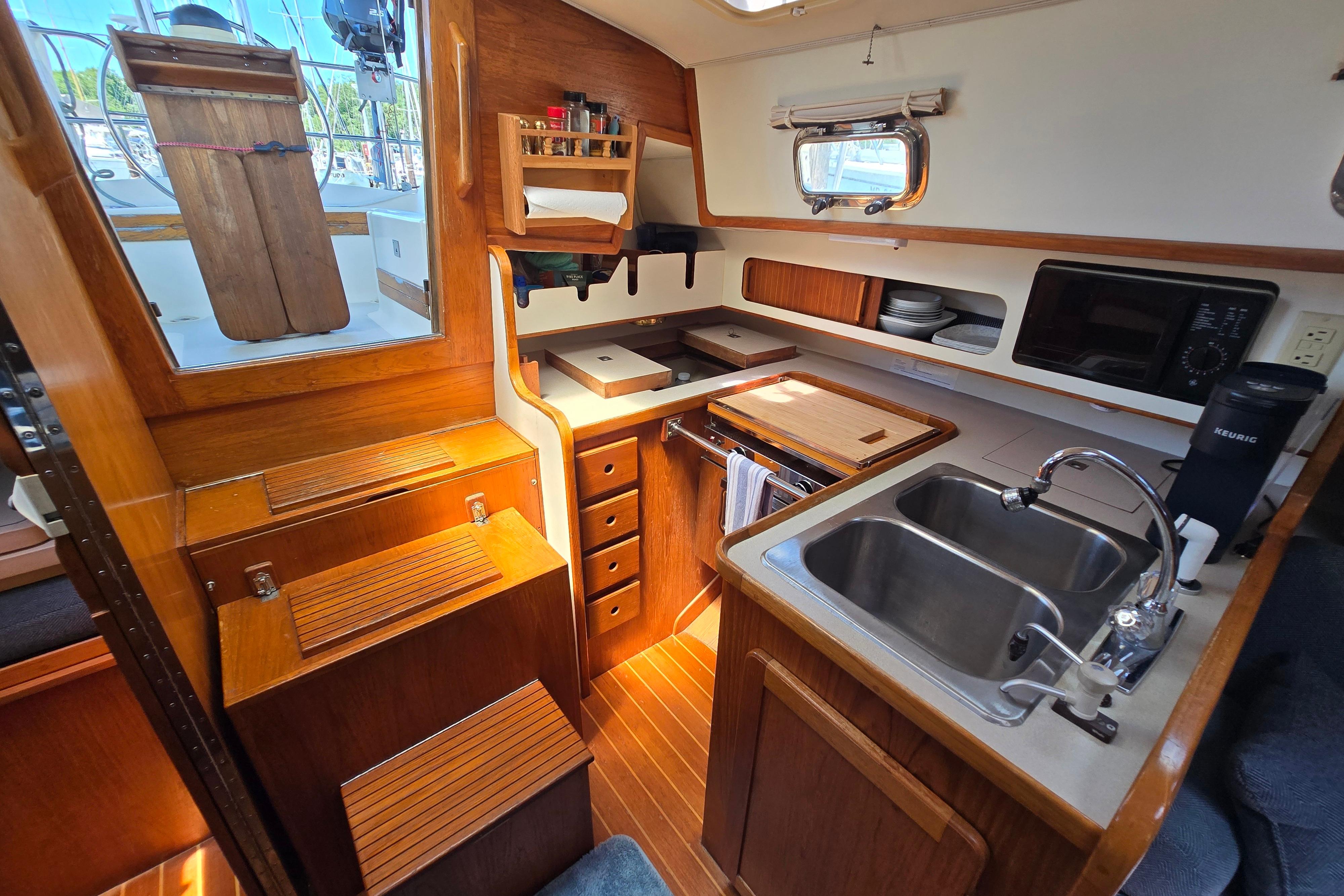 Cozy 1993 Caliber 35 yacht kitchen with wooden cabinetry, dual sink, and modern appliances.
