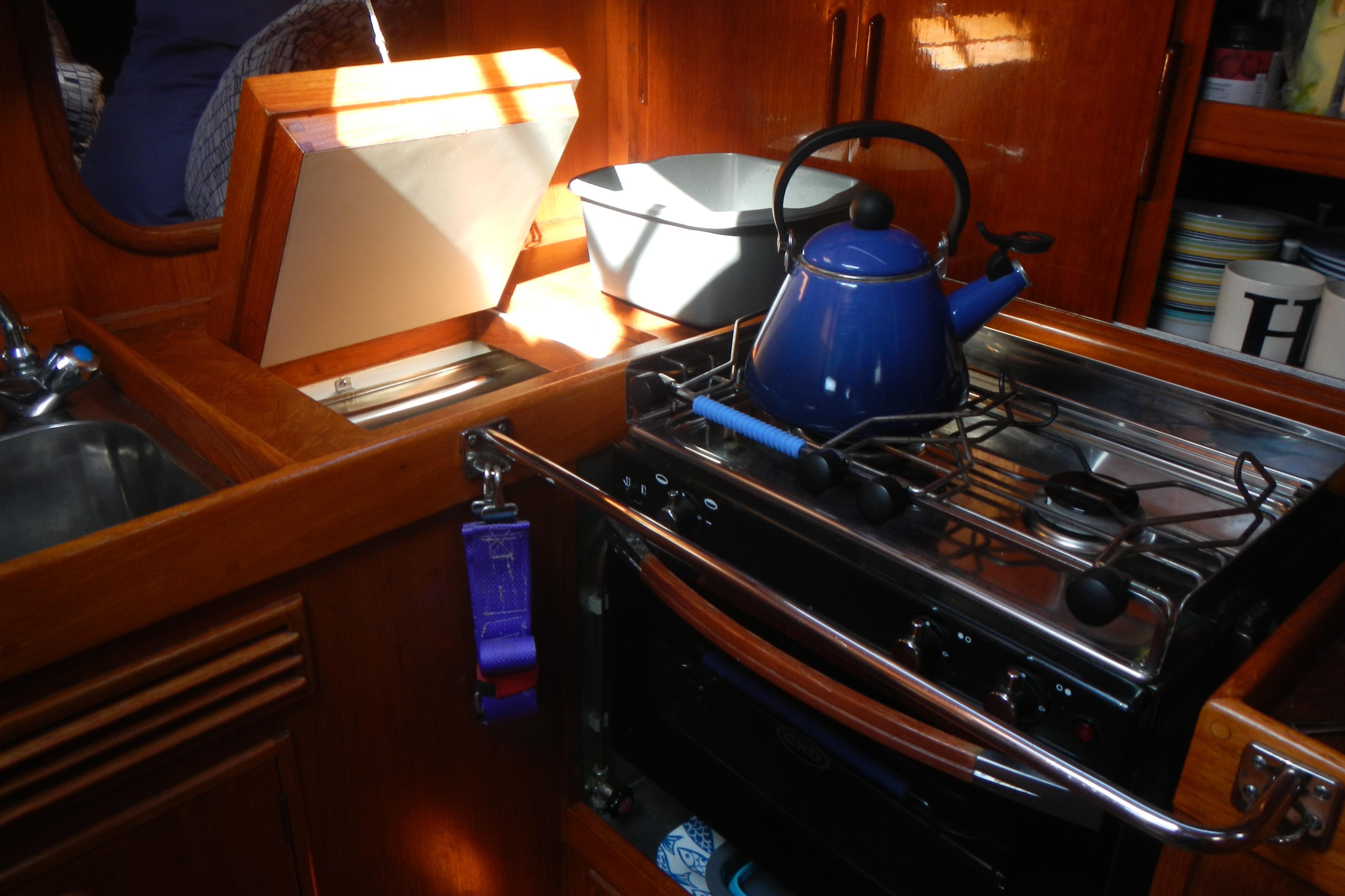 Cozy galley kitchen in 1980 Nautor Swan 411 yacht with blue kettle on stove.