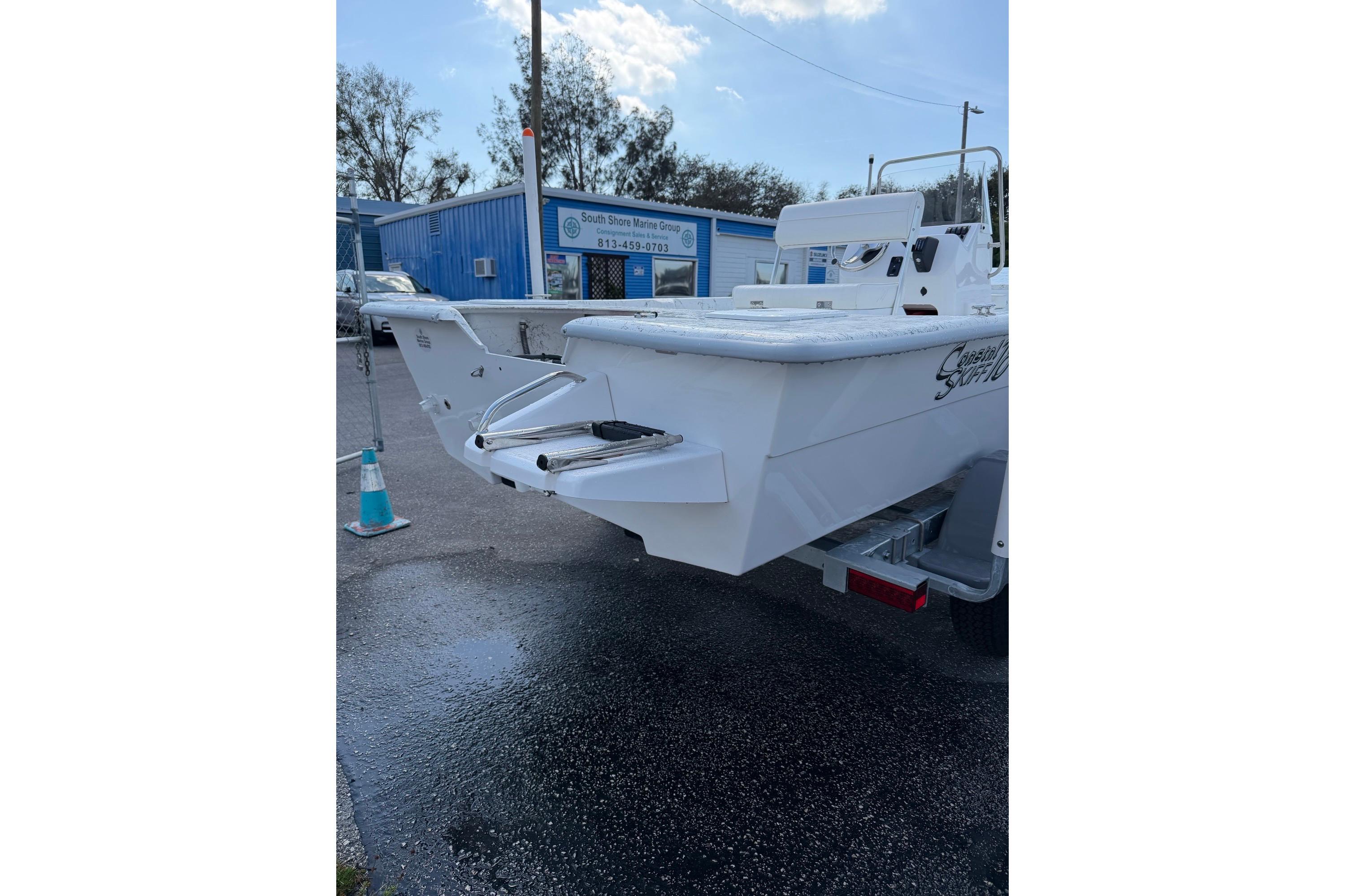 2027 Coastal Skiff 184 boat on trailer, parked outside marine shop.