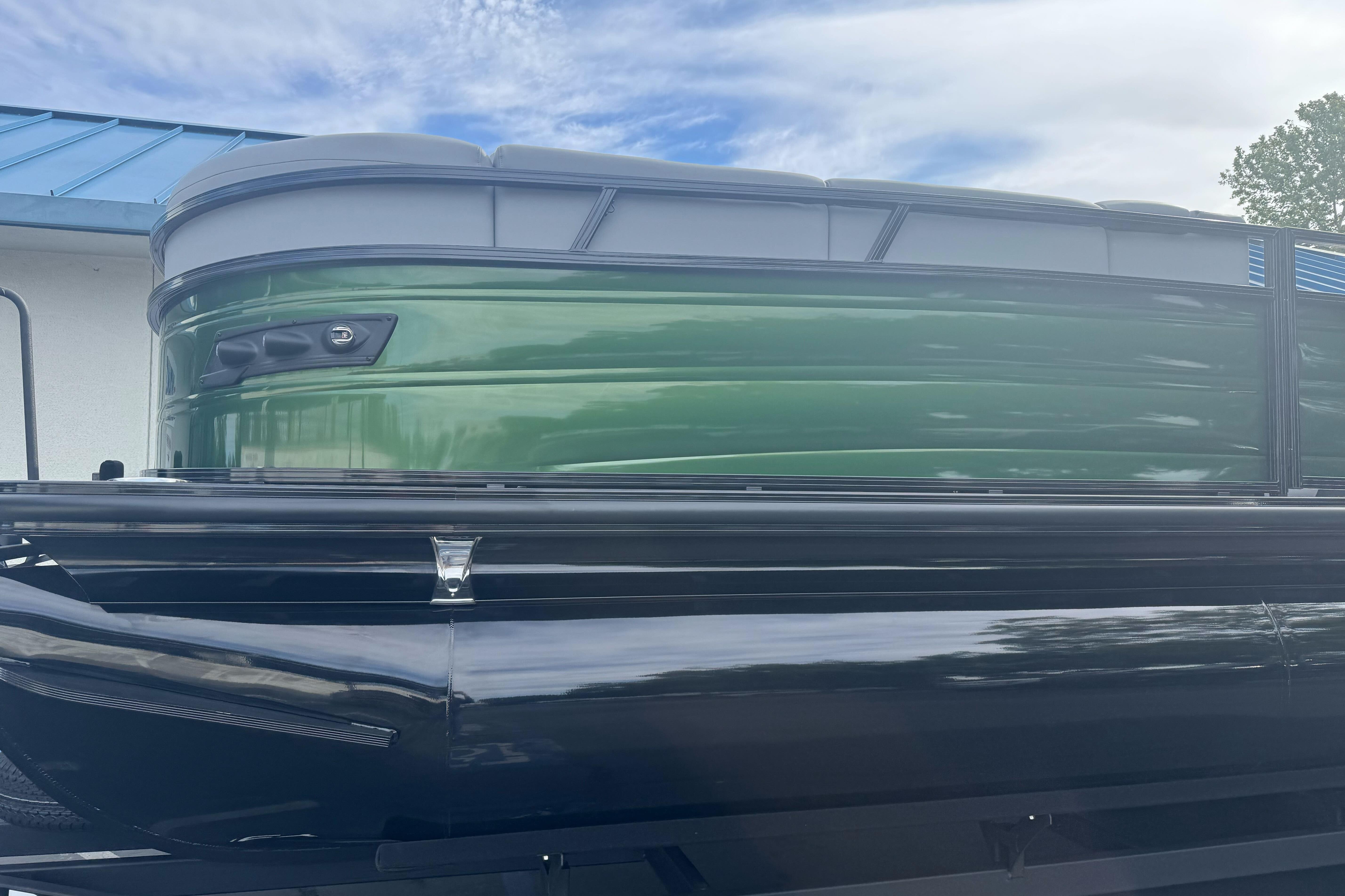 2026 Regency 250 DL pontoon boat with sleek green and black design under a cloudy sky.
