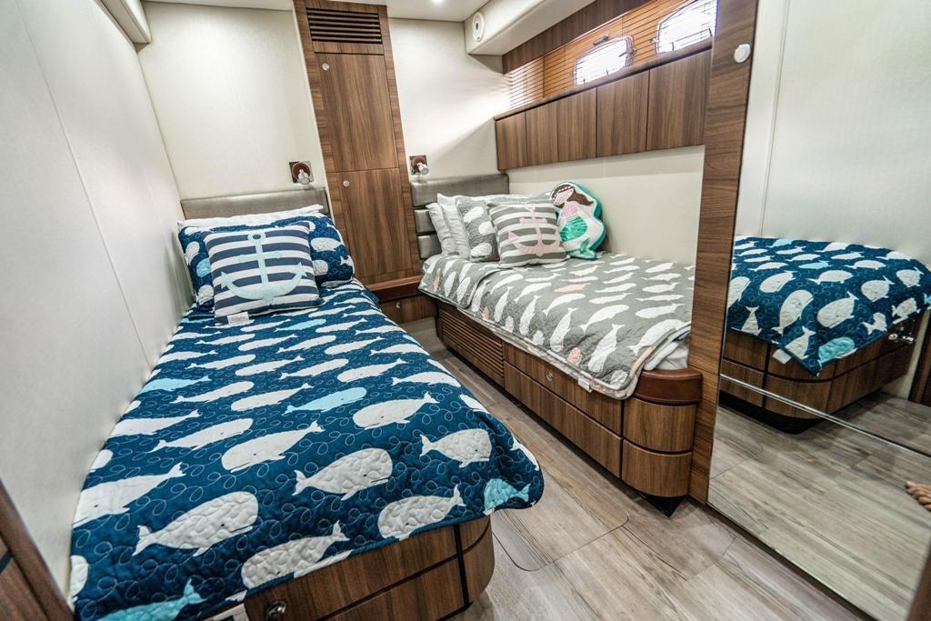 Luxurious twin cabin interior of 2020 Fairline 68 yacht with nautical-themed bedding.