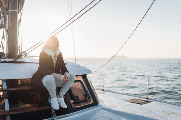 Person relaxing on a 2025 Nautitech 44 Open yacht at sea during sunset.