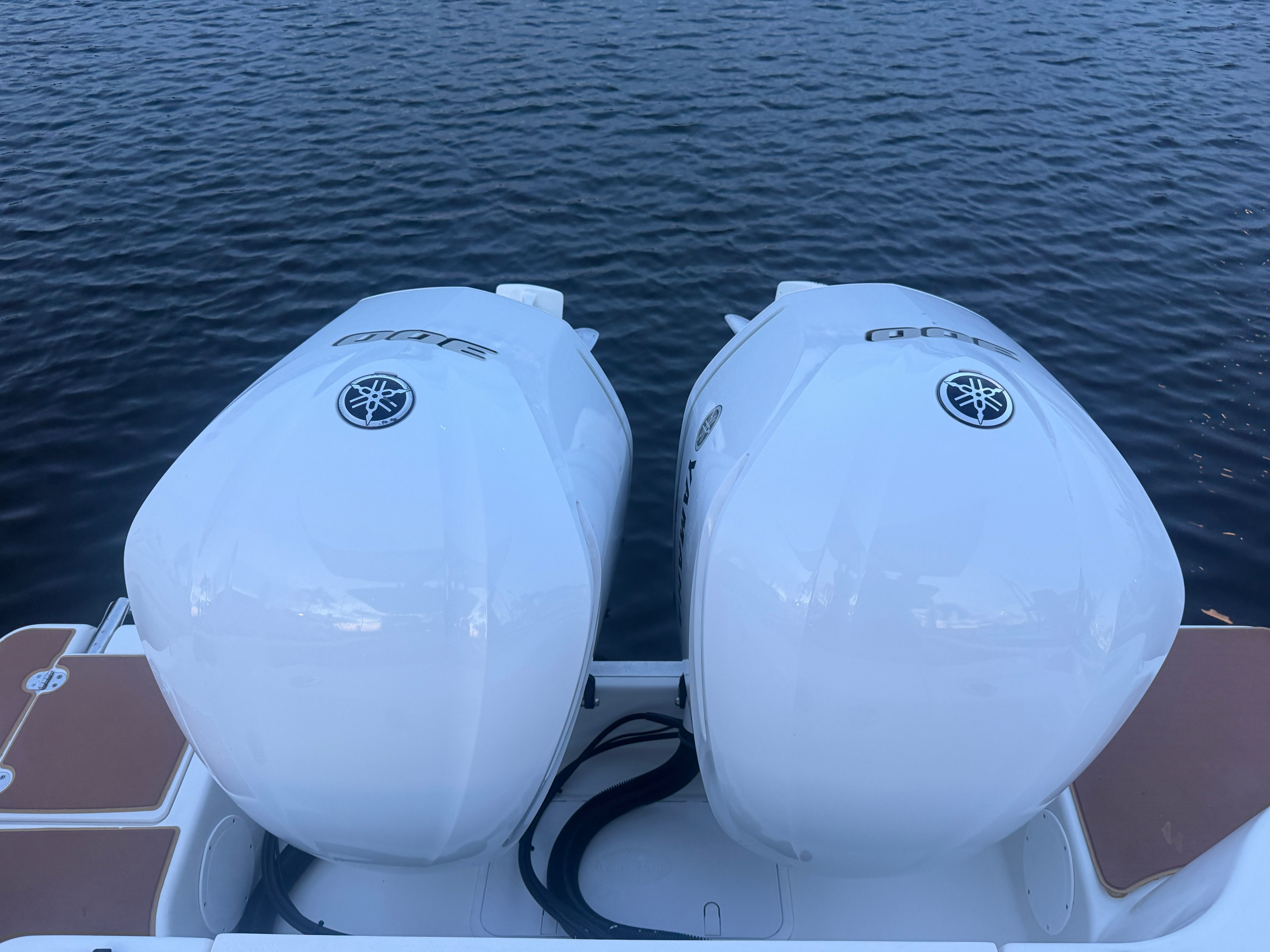 Two large Yamaha outboard engines are mounted on the stern of a boat on calm water.