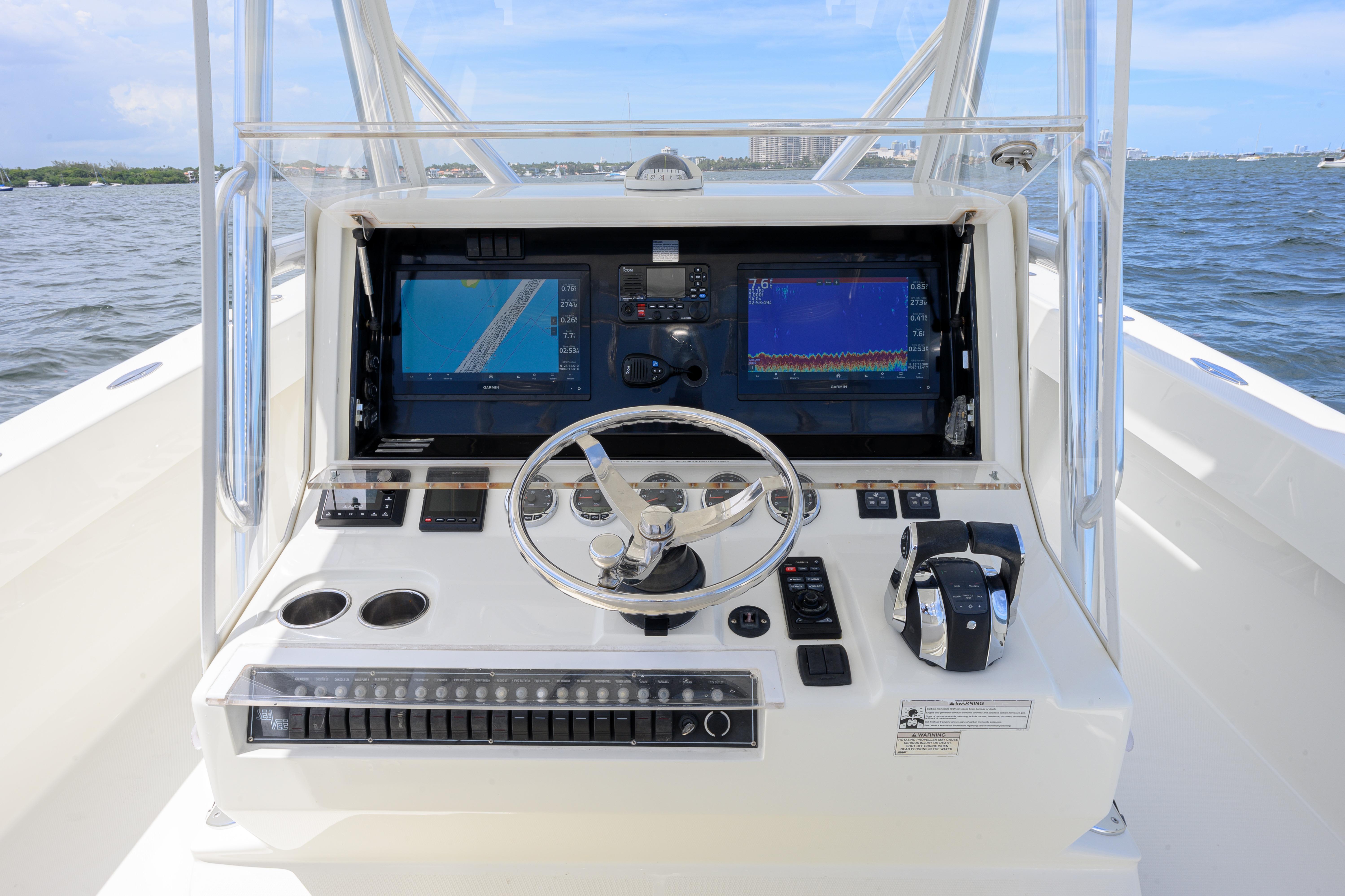 2017 SeaVee 390 boat helm with dual screens and steering wheel on open water.