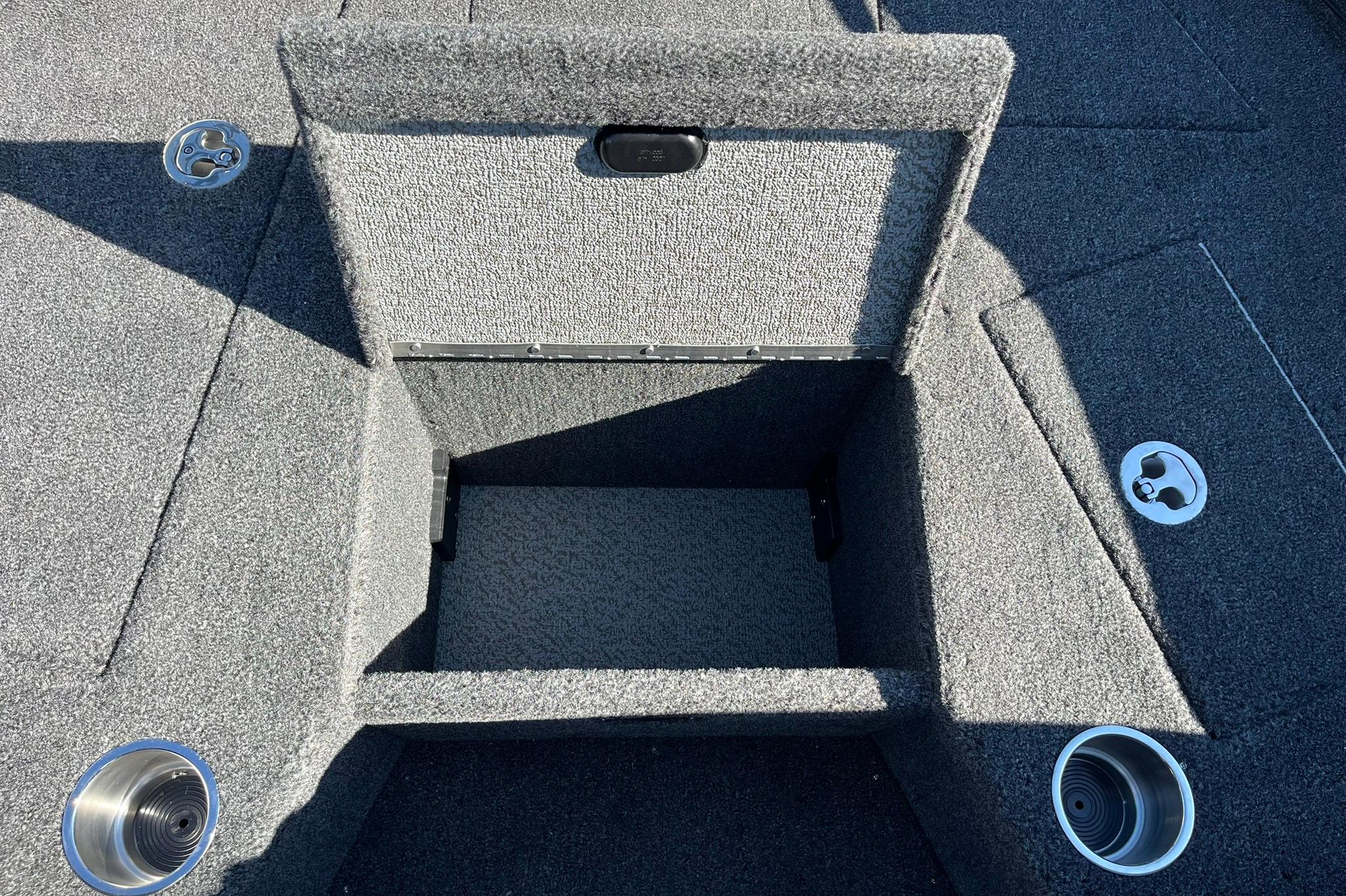 2026 Lund 2275 Baron boat interior storage compartment with carpeted finish and cup holders.