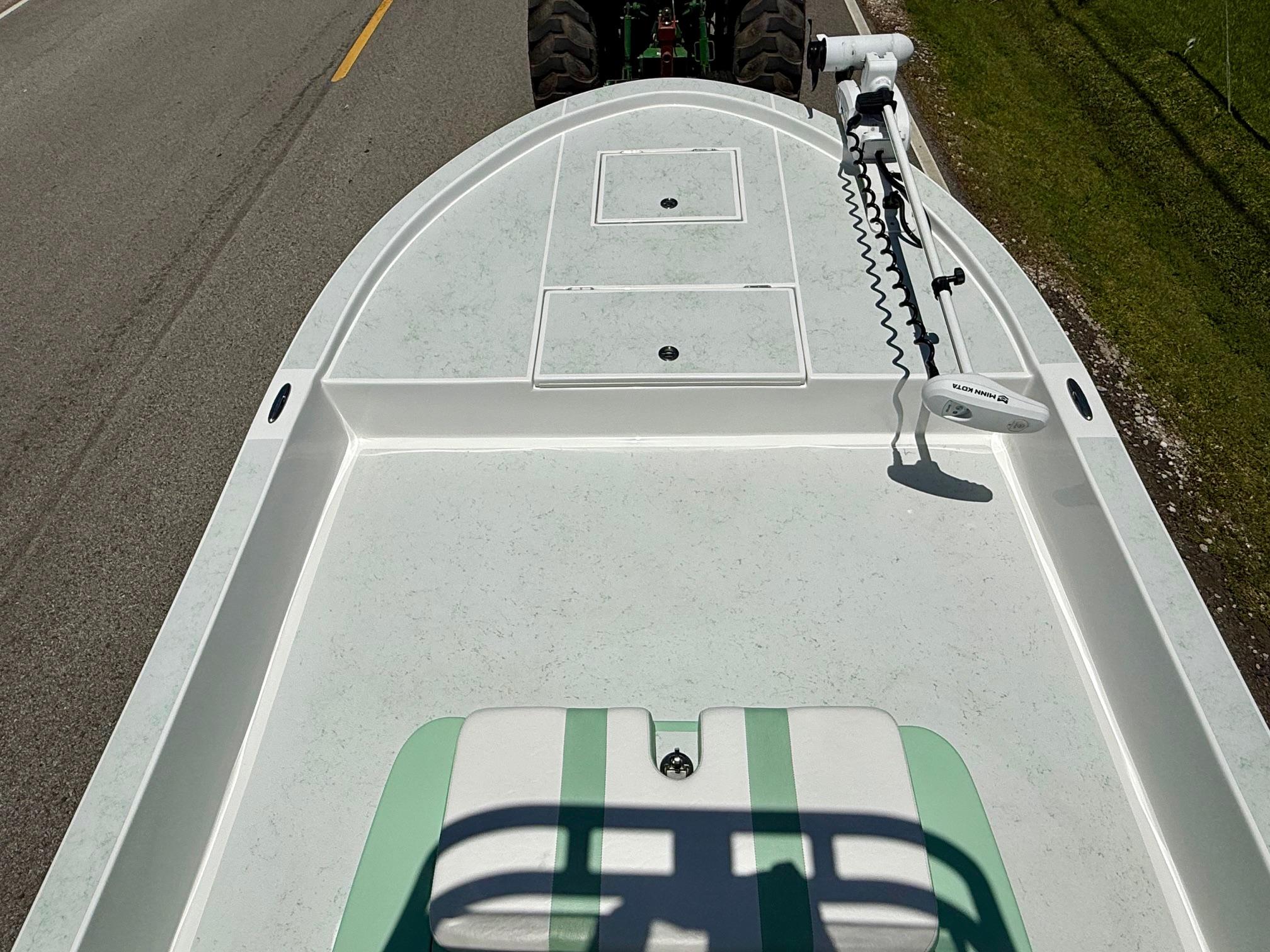 2023 Shallow Sport 24 Sport boat on road, featuring spacious deck and trolling motor.