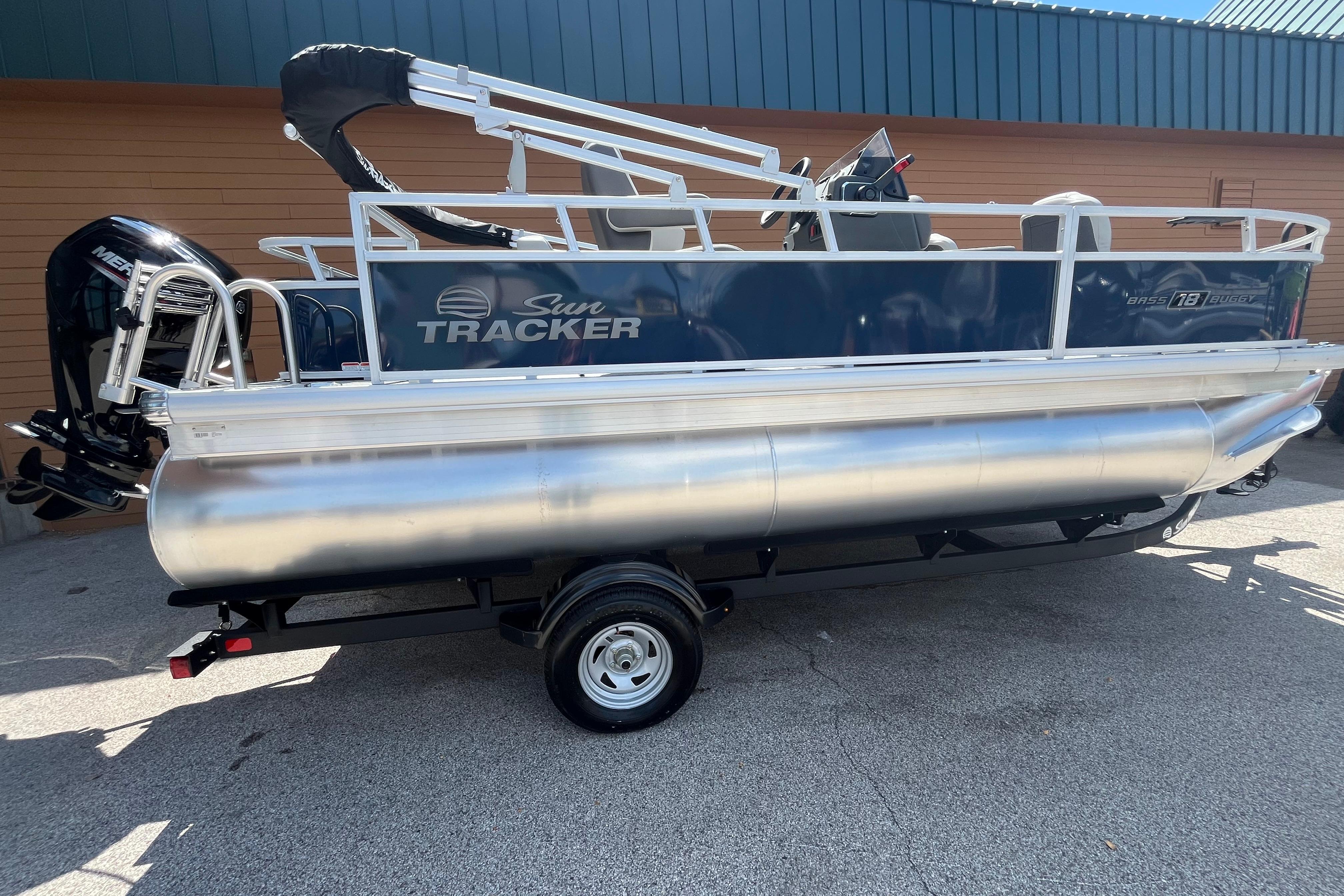2026 Sun Tracker Bass Buggy 18 DLX pontoon boat on trailer, side view.