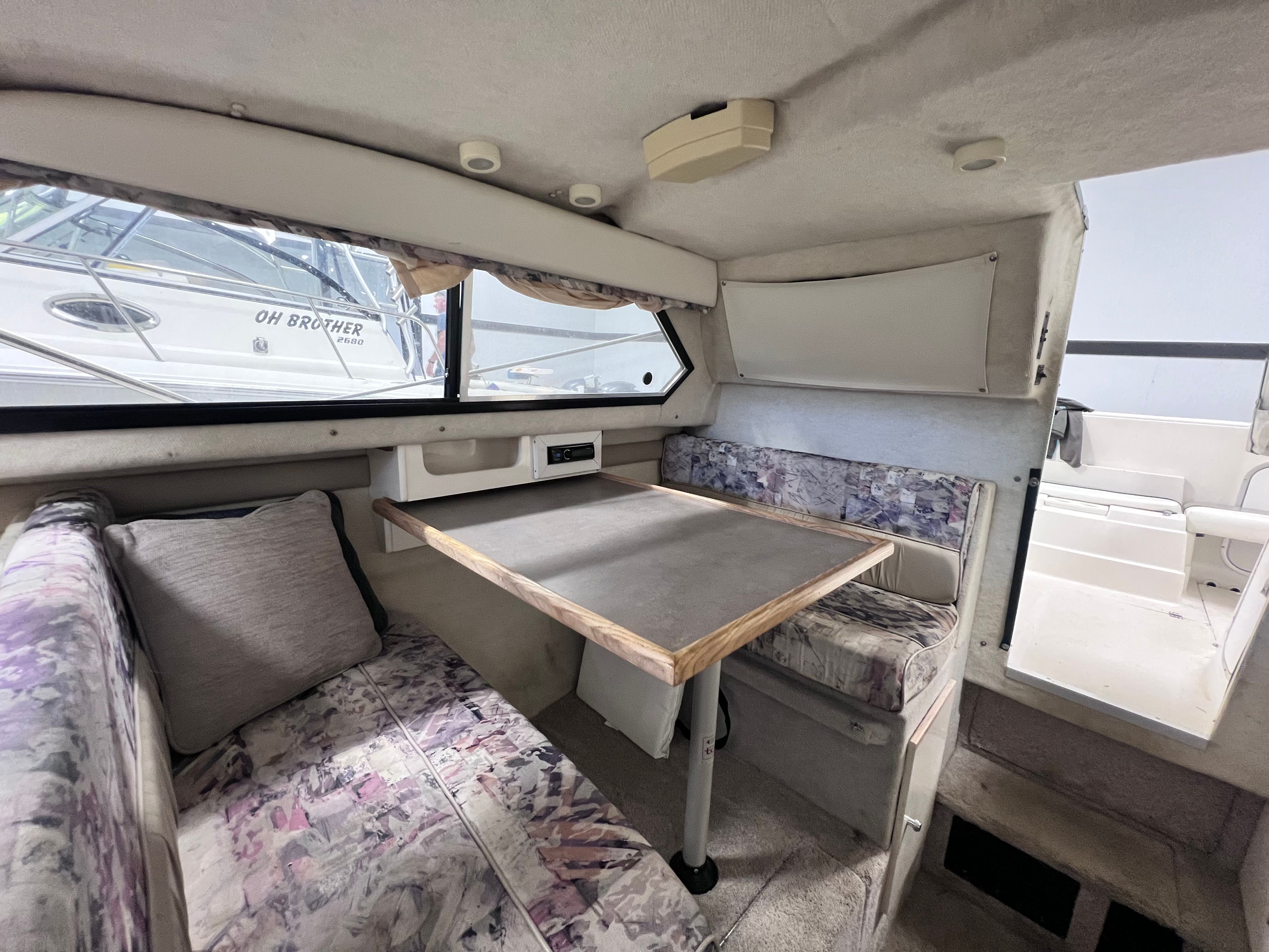 Interior of a 1997 Bayliner 2452 with table and seating area.