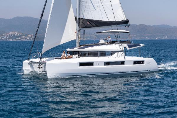 2025 Lagoon 51 ICONIC catamaran sailing on open sea with mountains in background.
