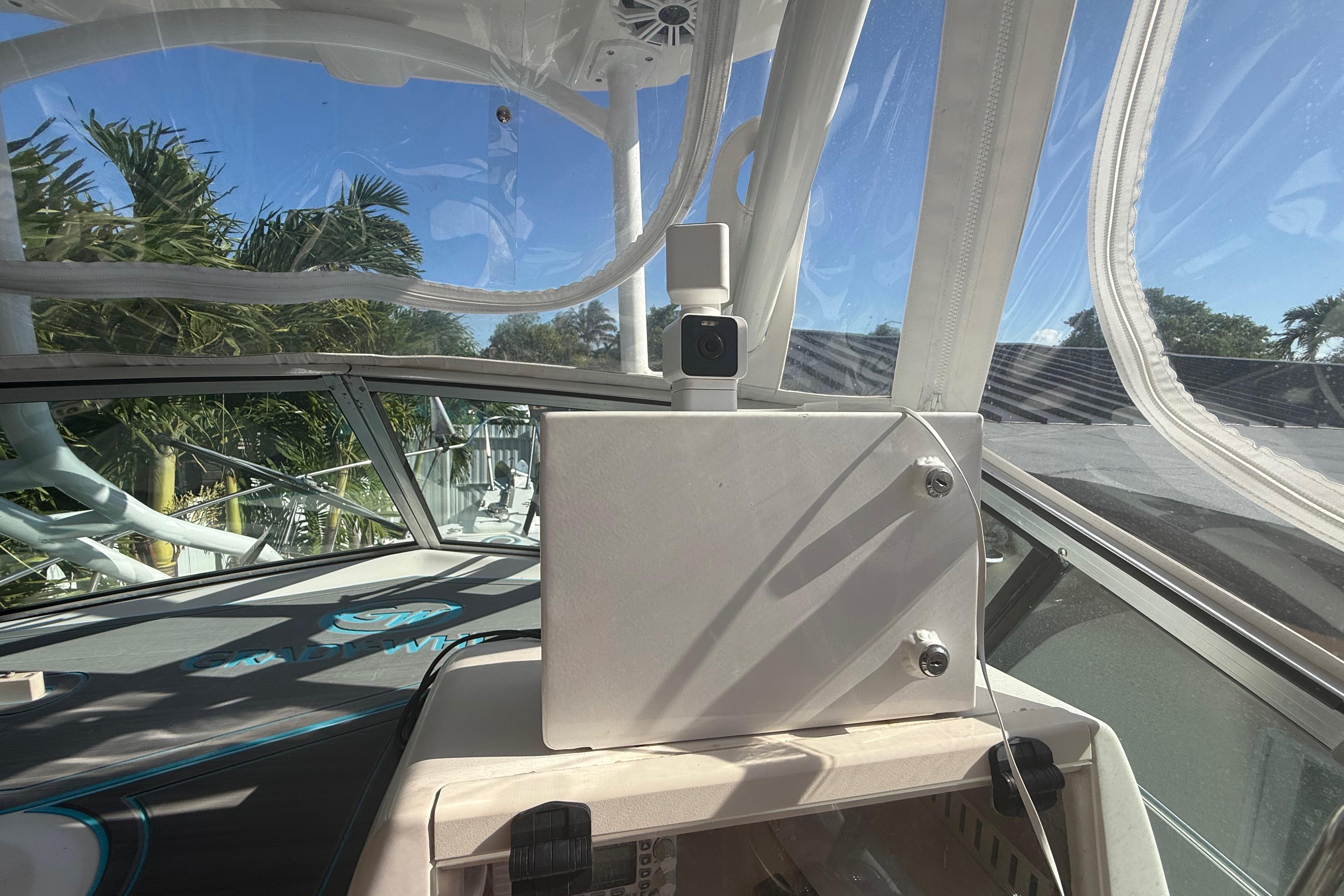 1996 Grady-White Sailfish 272 cockpit with clear canopy and lush greenery outside.